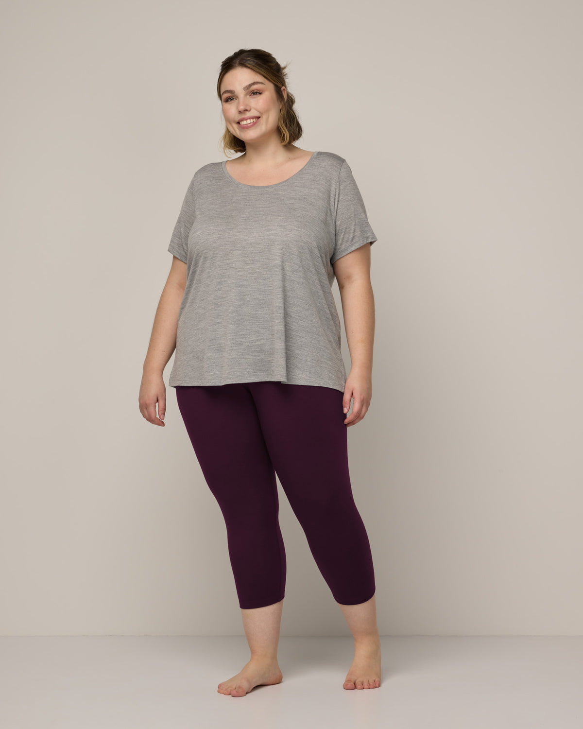 Model wearing Summit Crop Legging in Dark Marionberry, a deep berry purple color. Summit Crop Legging is a merino wool legging available in sizes XS-3X.