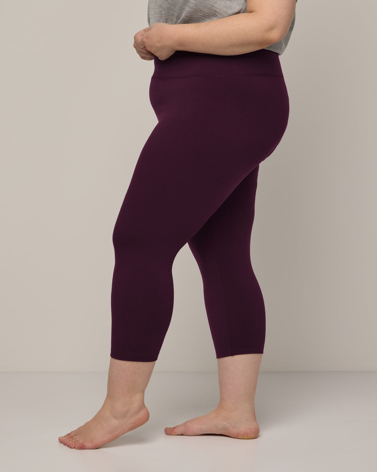 Model wearing Summit Crop Legging in Dark Marionberry, a deep berry purple color. Summit Crop Legging is a merino wool legging available in sizes XS-3X.