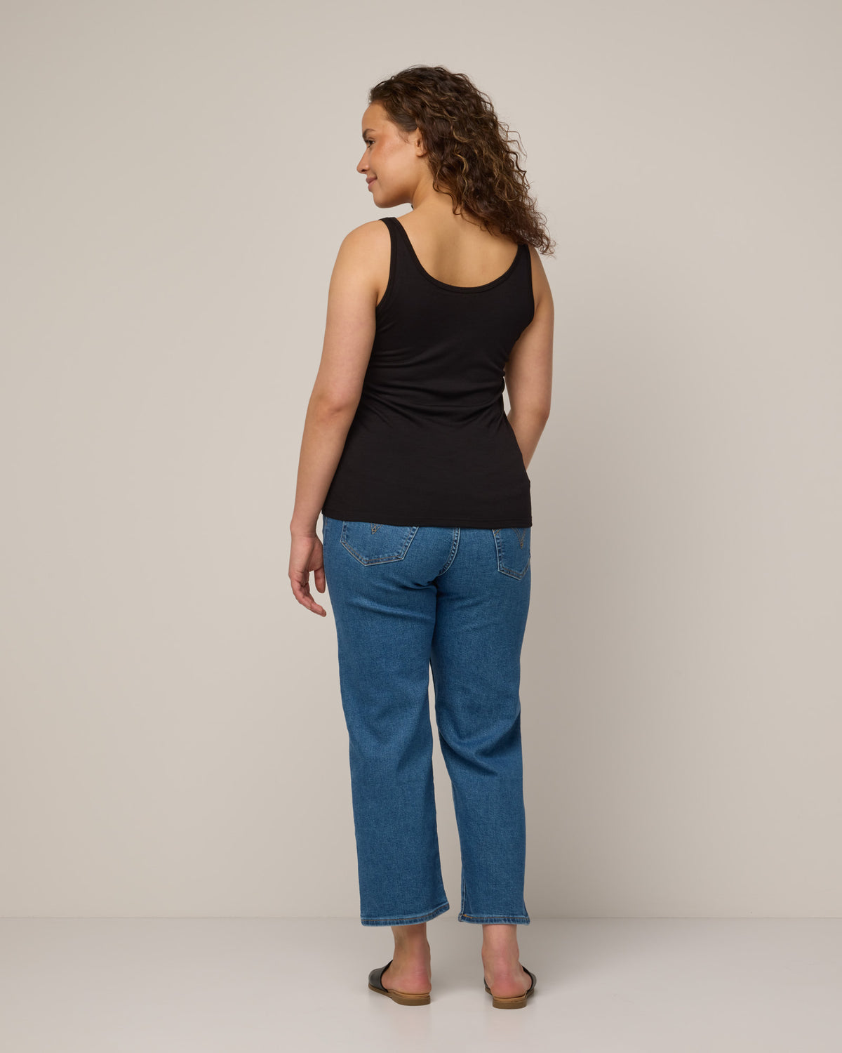 Model wearing Essential Layering Tank in Black. Essential Layering Tank is a merino wool sleeveless, reversible, slim fit top available in sizes XS-3X.