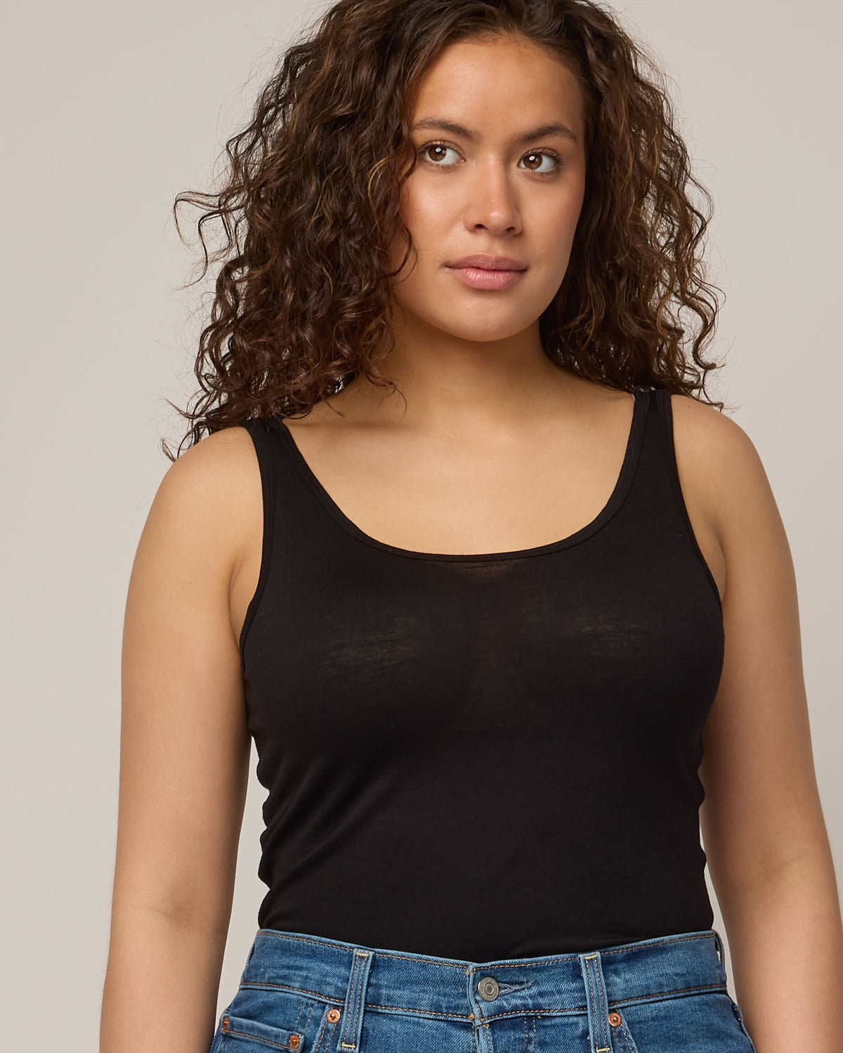 Model wearing Essential Layering Tank in Black. Essential Layering Tank is a merino wool sleeveless, reversible, slim fit top available in sizes XS-3X.