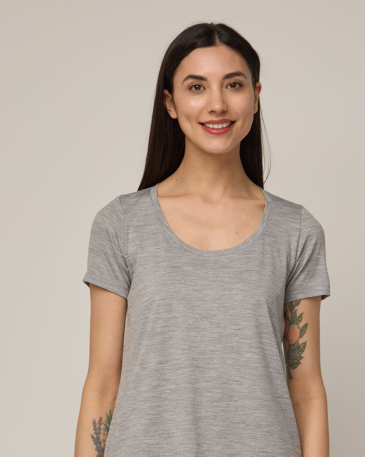 Model wearing Stella Signature Scoop Neck Tee in Gray Heather. Stella Signature Scoop Neck Tee is a merino wool short sleeve, scoop neck, relaxed fit tee available in sizes XS-3X.