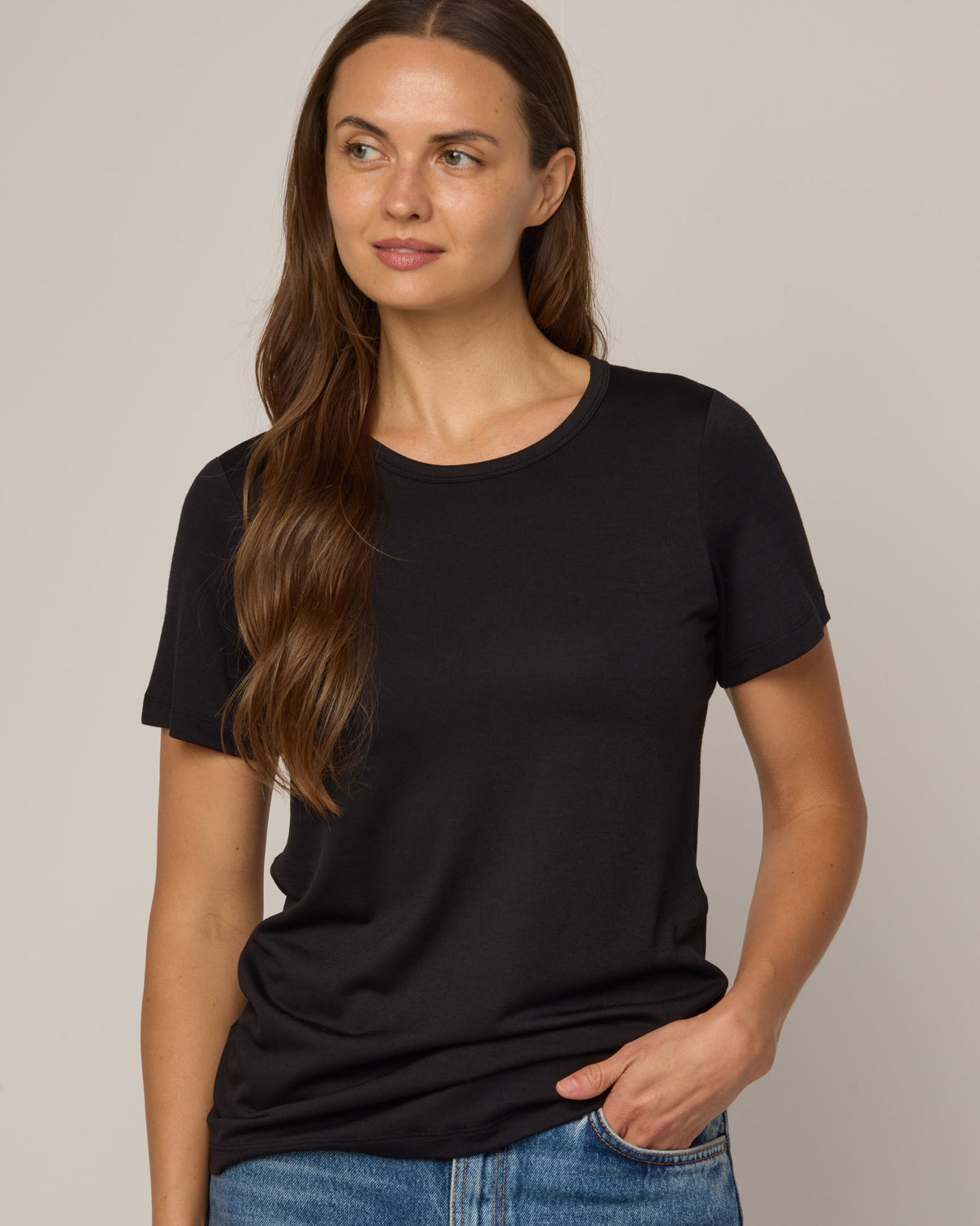 Model wearing Cara Signature Fitted Tee in Black. Cara Signature Fitted Tee is a merino wool short sleeve, crew neck, slim fit tee available in sizes XS-3X.