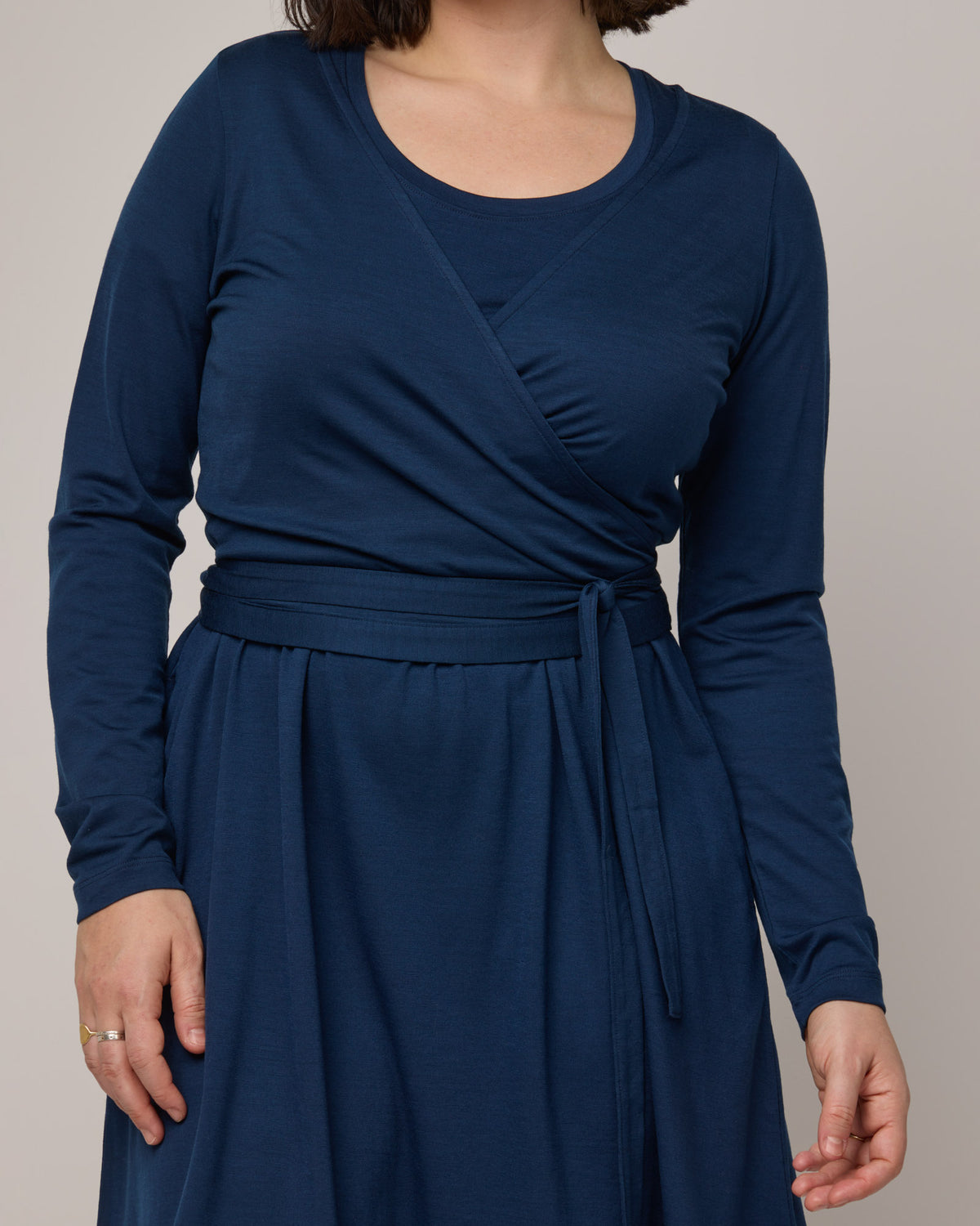 Model wearing Natalia Wrap Top in Marine Blue, a deep royal blue color. Natalia Wrap Top is a merino wool long sleeve, v-neck, slim fit top available in sizes XS-3X.