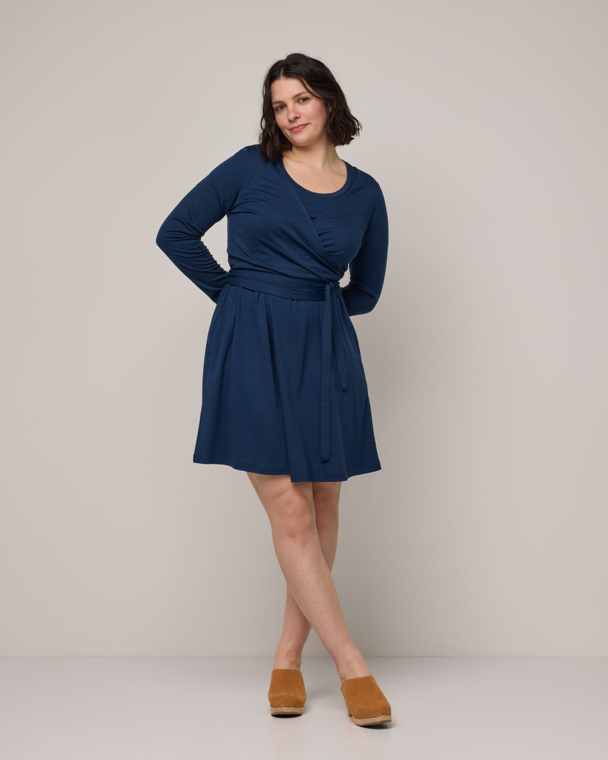 Model wearing Natalia Wrap Top in Marine Blue, a deep royal blue color. Natalia Wrap Top is a merino wool long sleeve, v-neck, slim fit top available in sizes XS-3X.