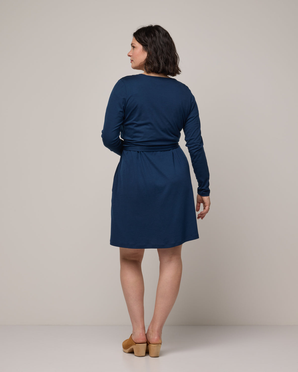 Model wearing Natalia Wrap Top in Marine Blue, a deep royal blue color. Natalia Wrap Top is a merino wool long sleeve, v-neck, slim fit top available in sizes XS-3X.