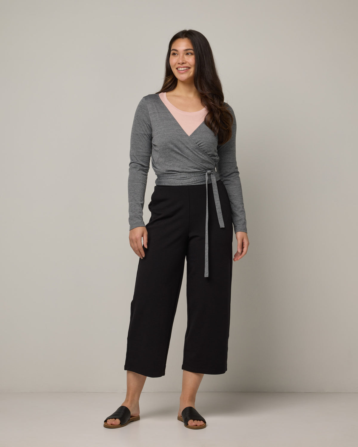 Model wearing Natalia Wrap Top in Charcoal Heather. Natalia Wrap Top is a merino wool long sleeve, v-neck, slim fit top available in sizes XS-3X.