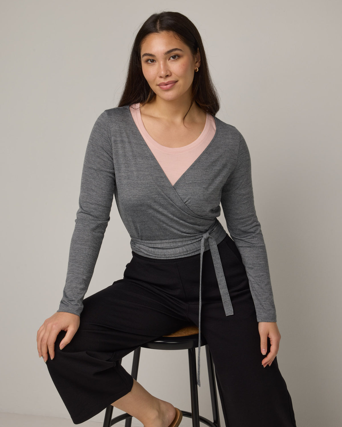 Model wearing Natalia Wrap Top in Charcoal Heather. Natalia Wrap Top is a merino wool long sleeve, v-neck, slim fit top available in sizes XS-3X.