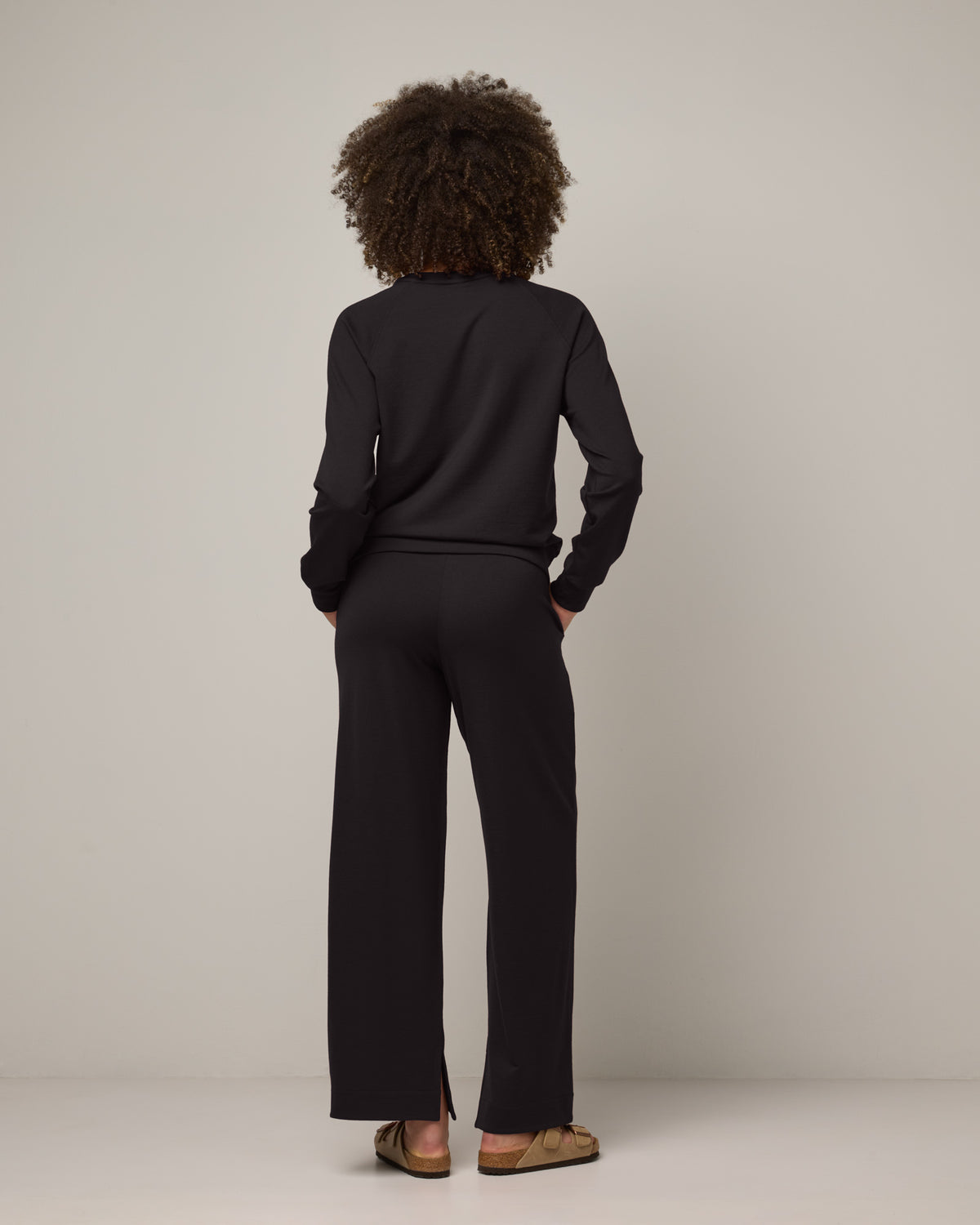 Model wearing Aspen Wide Leg Sweatpants in Black. Aspen Wide Leg Sweatpants is a merino wool sweatpant with pockets available in sizes XS-3X.