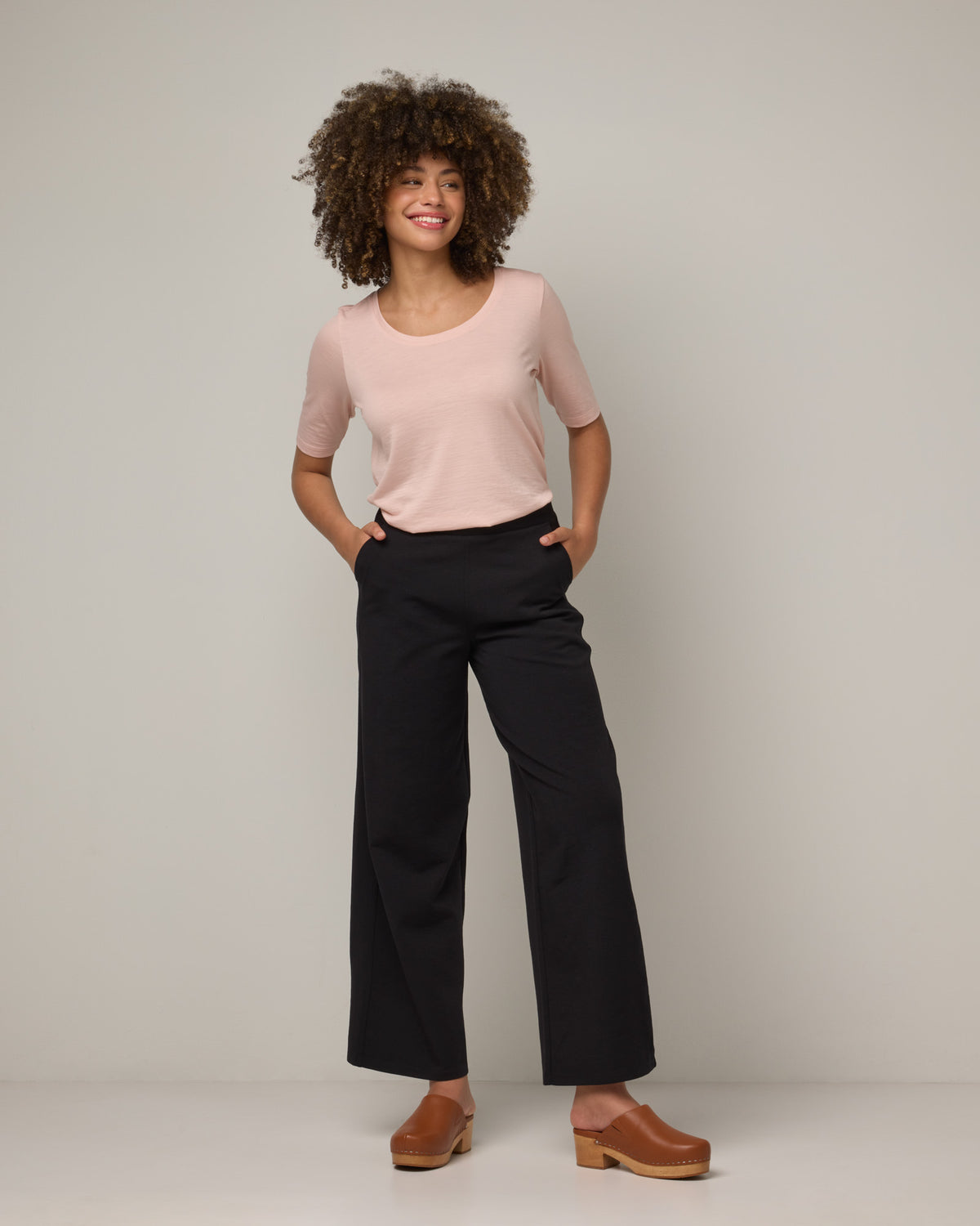 Model wearing Lane Wide Leg Ponte Pant in Black. Lane Wide Leg Ponte Pant is a merino wool pant with pockets available in sizes XS-3X Regular, XS-XXL Long.