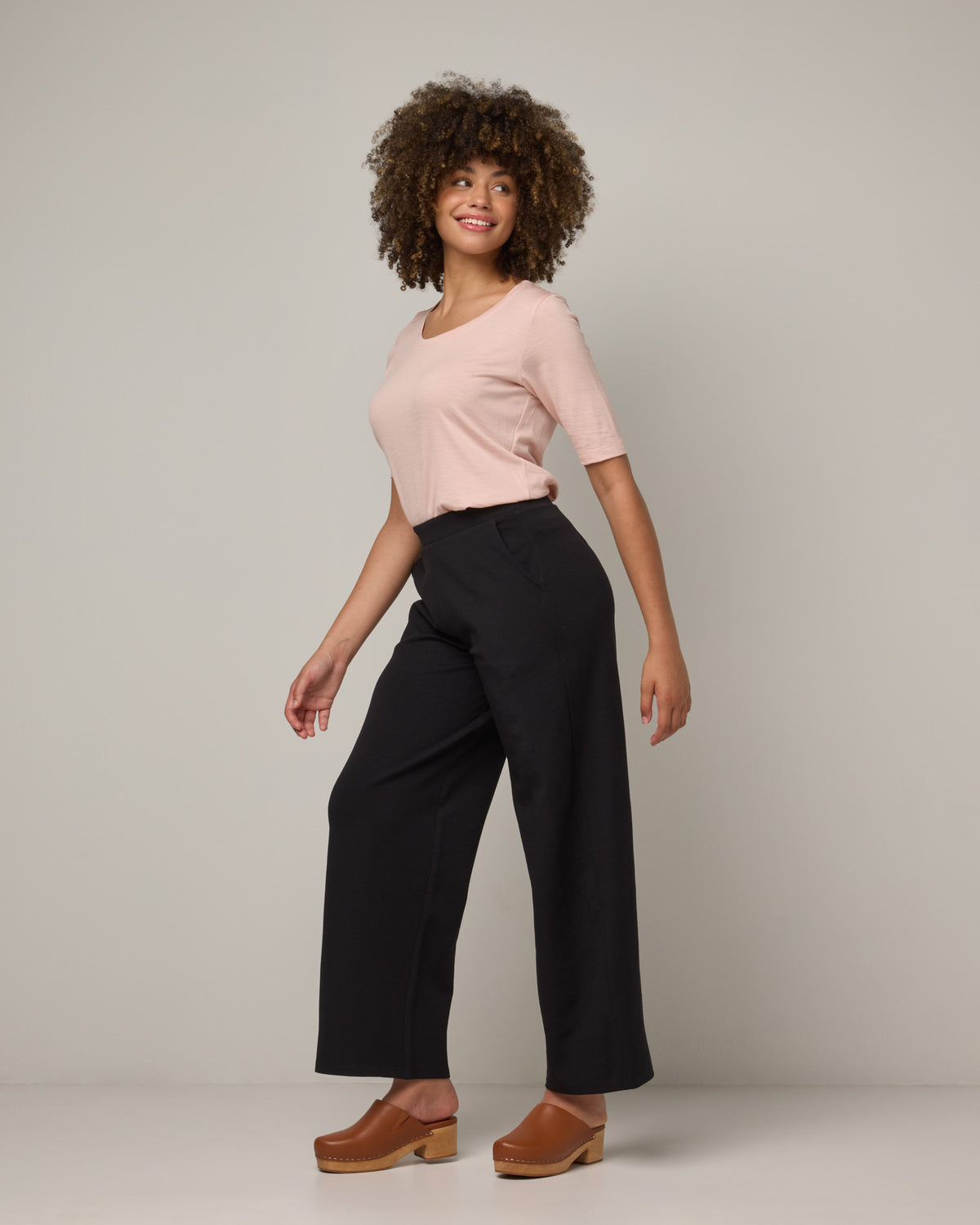Model wearing Lane Wide Leg Ponte Pant in Black. Lane Wide Leg Ponte Pant is a merino wool pant with pockets available in sizes XS-3X Regular, XS-XXL Long.