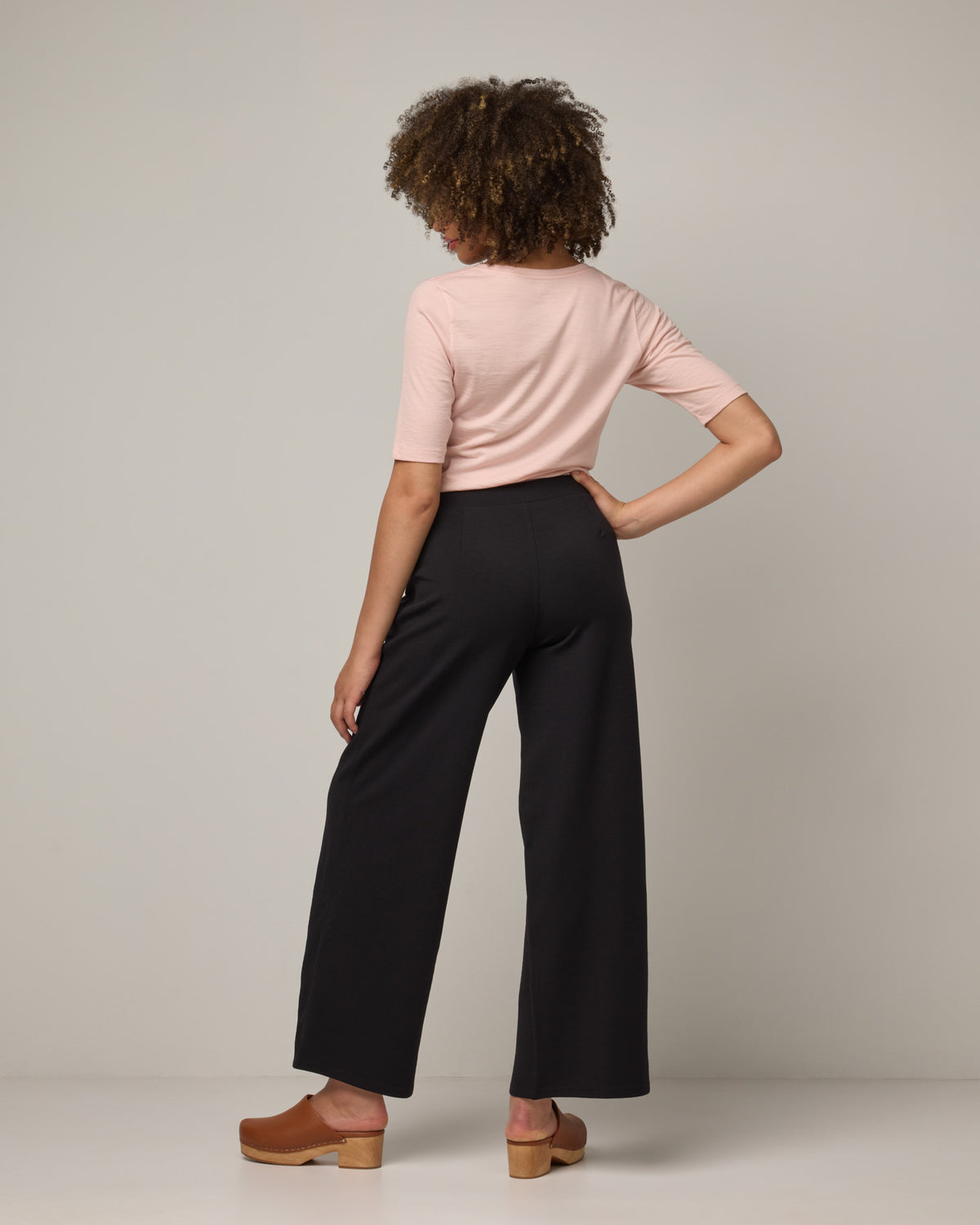 Model wearing Lane Wide Leg Ponte Pant in Black. Lane Wide Leg Ponte Pant is a merino wool pant with pockets available in sizes XS-3X Regular, XS-XXL Long.
