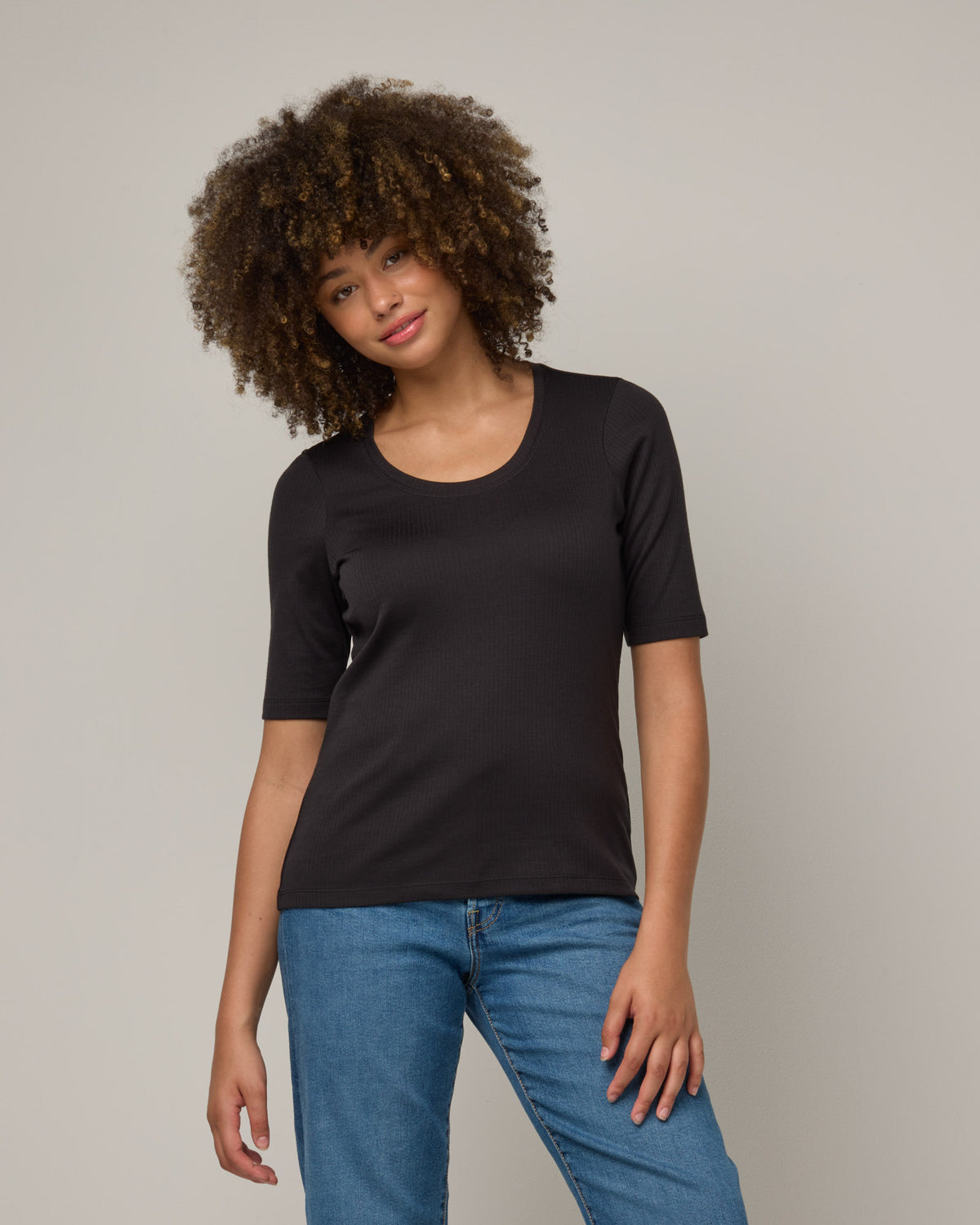 Model wearing Celine Ribbed Elbow Sleeve Tee in Black. Celine Ribbed Elbow Sleeve Tee is a merino wool short sleeve, scoop neck, slim fit tee available in sizes XS-3X.