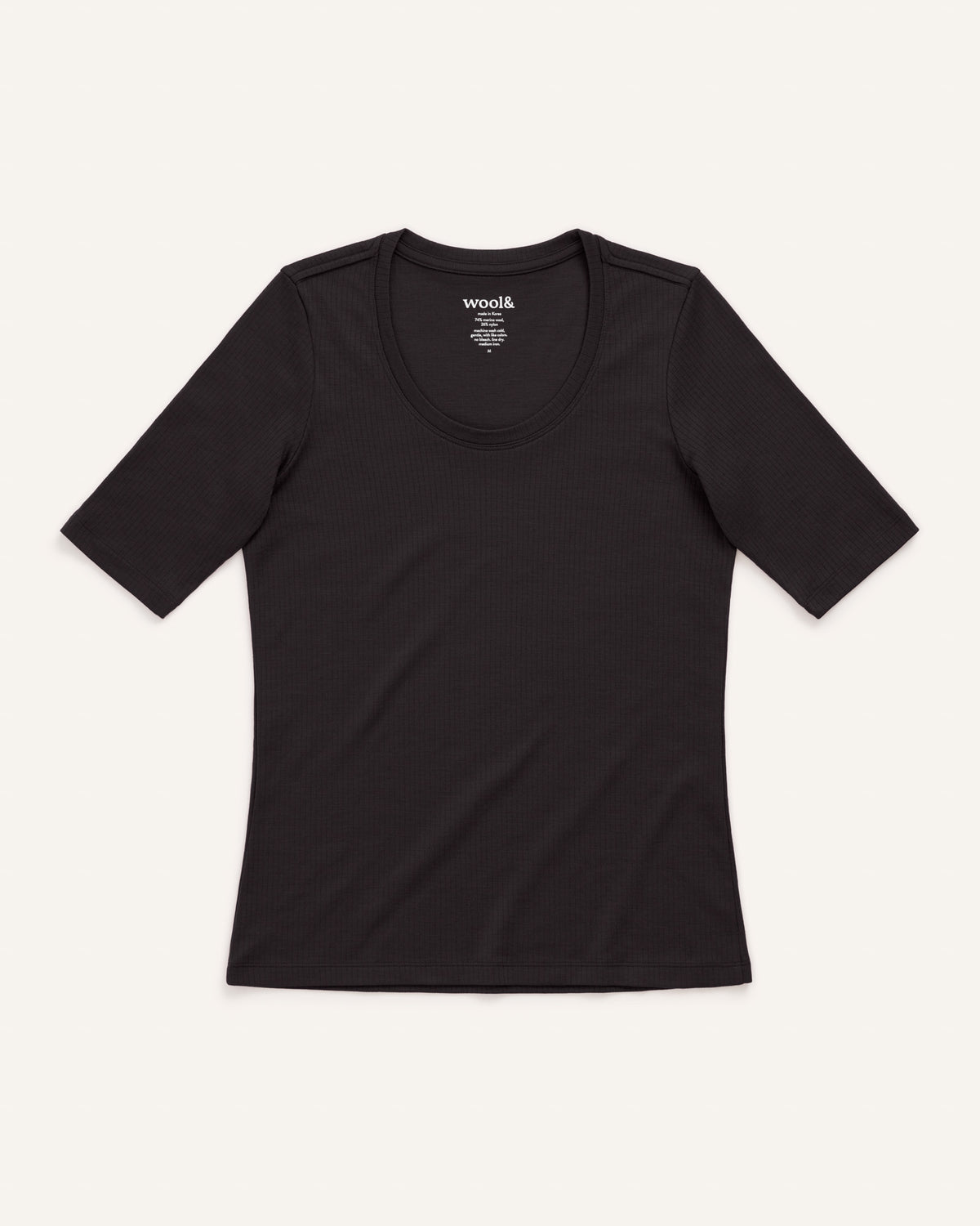 Laydown of Celine Ribbed Elbow Sleeve Tee in Black. Celine Ribbed Elbow Sleeve Tee is a merino wool short sleeve, scoop neck, slim fit tee available in sizes XS-3X.