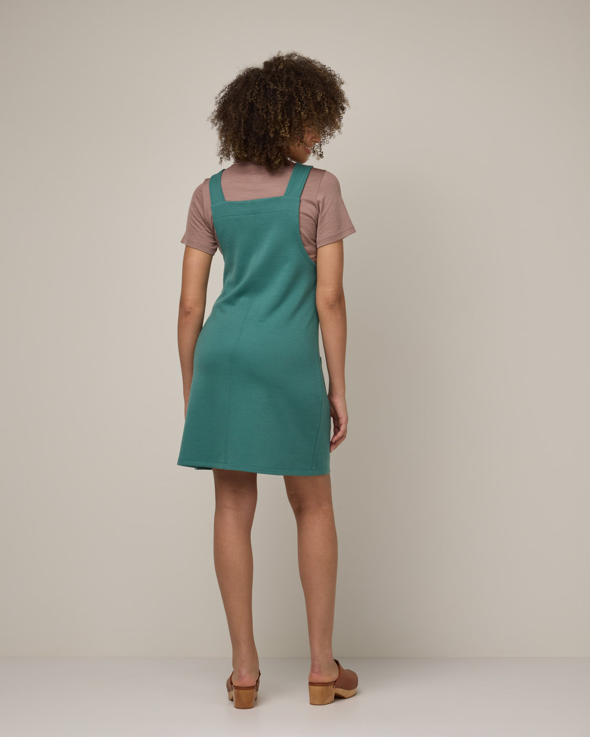 Model wearing Goldie Pinafore Dress in Silver Jade, a soft green-blue color. Goldie Pinafore Dress is a merino wool sleeveless, square neck, knee length shift dress with pockets available in sizes XS-3X.