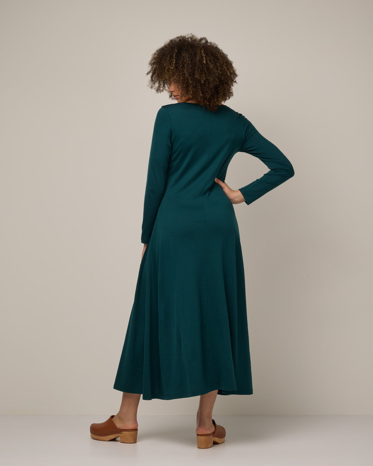 Model wearing Valerie Maxi Dress in Pine, a saturated forest green color. Valerie Maxi Dress is a merino wool long sleeve, scoop neck, maxi swing dress available in sizes XS-XXL.