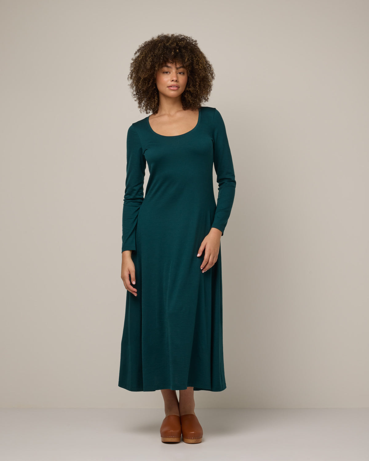 Model wearing Valerie Maxi Dress in Pine, a saturated forest green color. Valerie Maxi Dress is a merino wool long sleeve, scoop neck, maxi swing dress available in sizes XS-XXL.