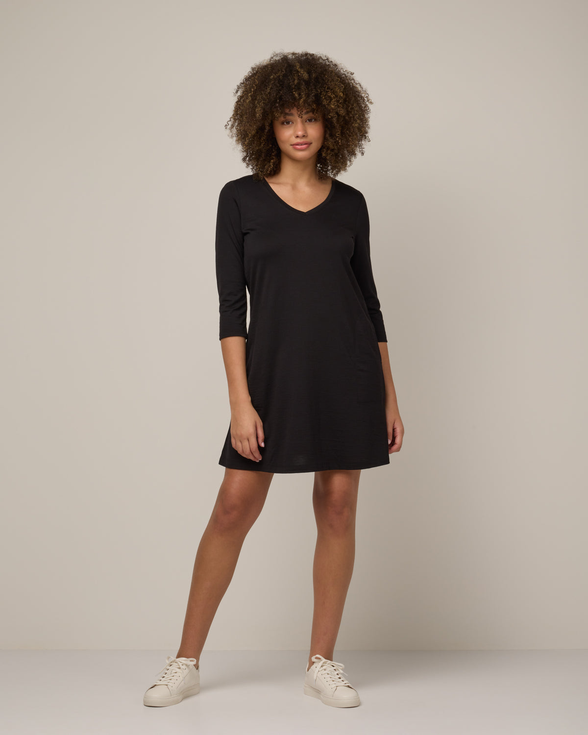 Model wearing Willow Swing Dress in Black. Willow Swing Dress is a merino wool long sleeve, v-neck, knee length swing dress with pockets available in sizes XS-3X Regular, XS-3X Long.