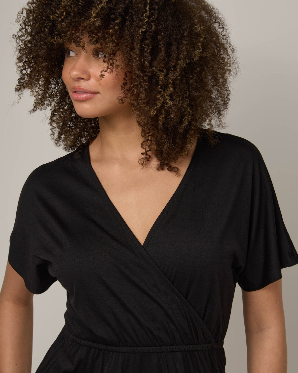 Model wearing Brooklyn Reversible Dress in Black. Brooklyn Reversible Dress is a merino wool short sleeve, reversible, knee length fit & flare dress with pockets available in sizes XS-3X Regular, XS-XL Long.