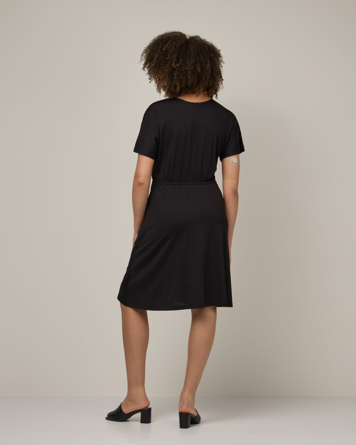 Model wearing Brooklyn Reversible Dress in Black. Brooklyn Reversible Dress is a merino wool short sleeve, reversible, knee length fit & flare dress with pockets available in sizes XS-3X Regular, XS-XL Long.