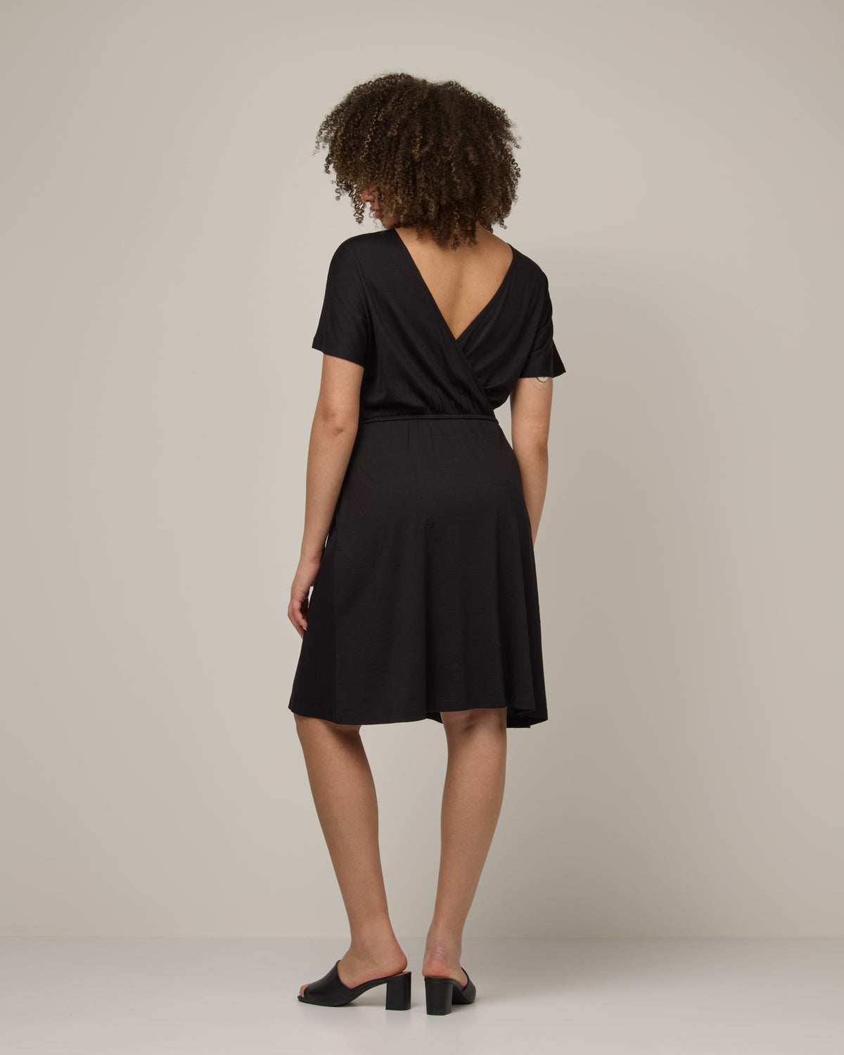 Model wearing Brooklyn Reversible Dress in Black. Brooklyn Reversible Dress is a merino wool short sleeve, reversible, knee length fit & flare dress with pockets available in sizes XS-3X Regular, XS-XL Long.