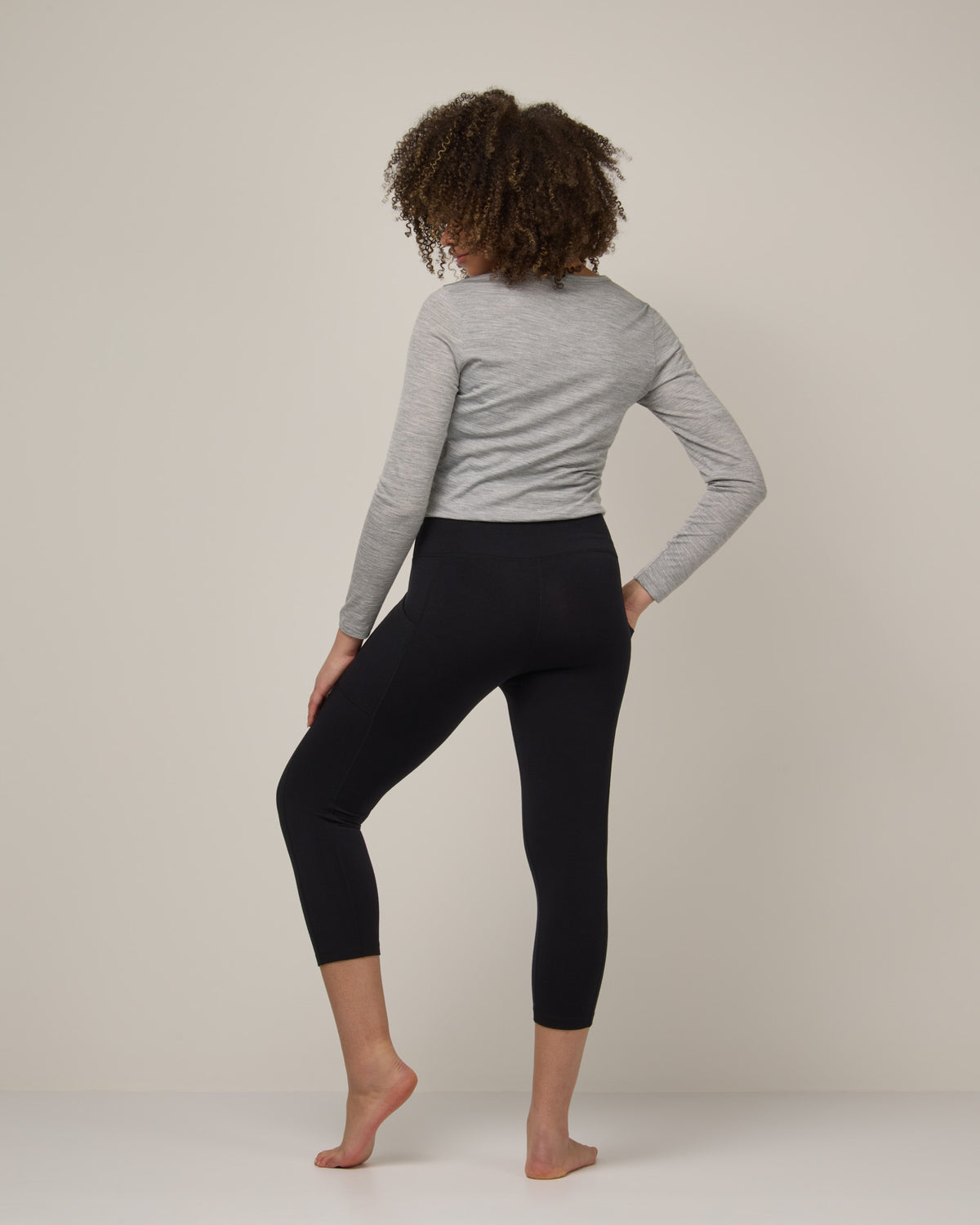 Model wearing Summit Pocket Crop Legging in Black. Summit Pocket Crop Legging is a merino wool legging with pockets available in sizes XS-3X.
