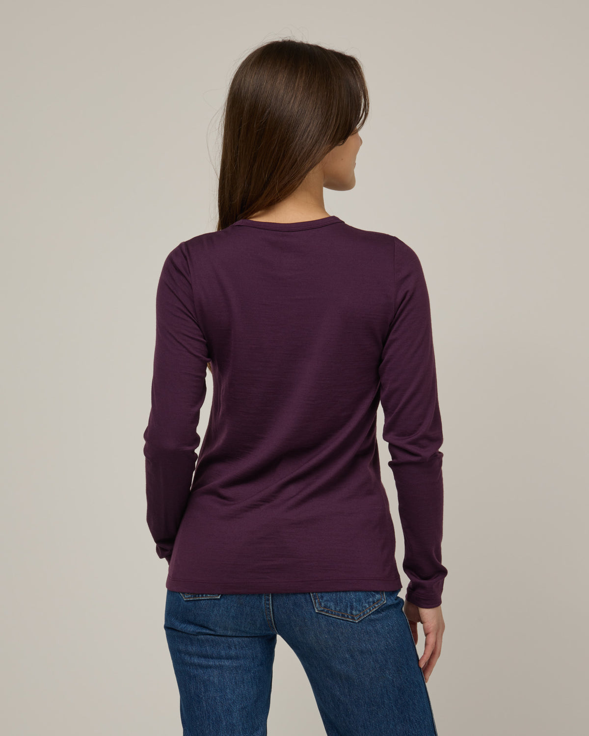Model wearing Sloan Signature Fitted Tee in Marionberry, a dark berry purple color. Sloan Signature Fitted Tee is a merino wool long sleeve, crew neck, slim fit tee available in sizes XS-3X.