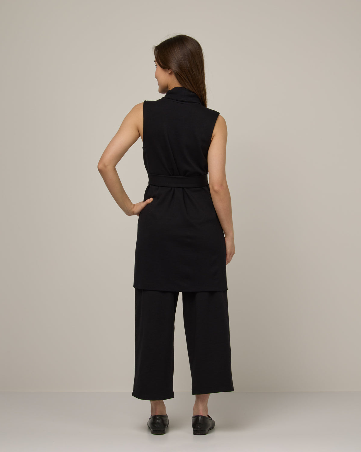 Model wearing Dylan Belted Vest in Black. Dylan Belted Vest is a merino wool sleevelessvest with pockets available in sizes XS-3X.
