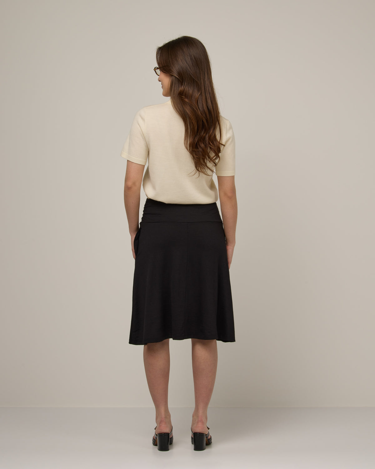Model wearing Helena Skirt in Black. Helena Skirt is a merino wool knee length skirt with pockets available in sizes XS-3X.