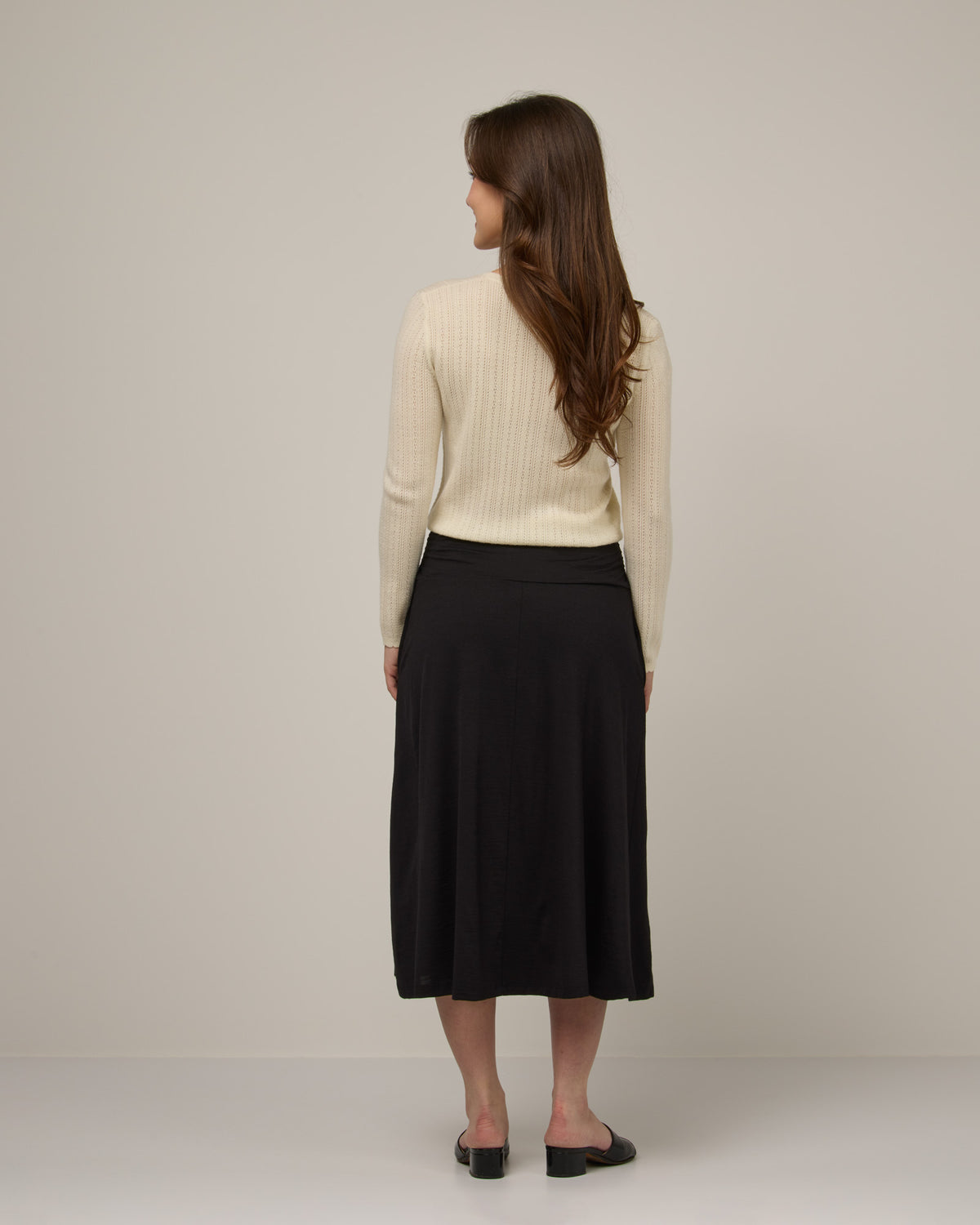 Model wearing Helena Midi Skirt in Black. Helena Midi Skirt is a merino wool midi skirt with pockets available in sizes XS-3X.