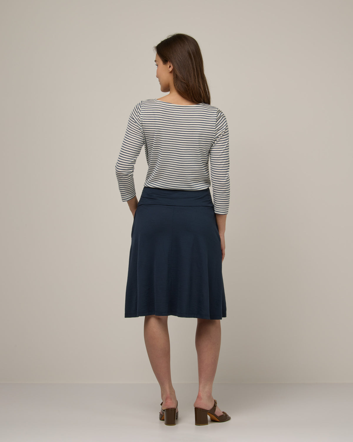 Model wearing Helena Skirt in Washed Navy. Helena Skirt is a merino wool knee length skirt with pockets available in sizes XS-3X.