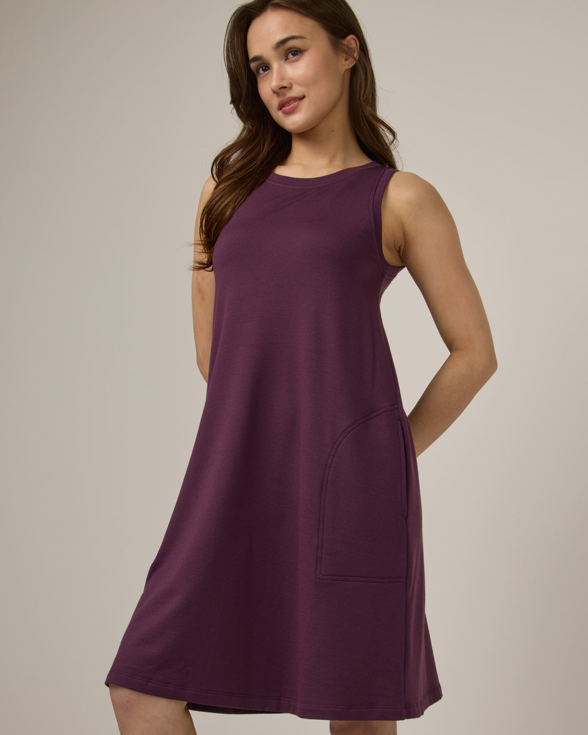 Model wearing Sierra Tank Dress in Marionberry, a dark berry purple color. Sierra Tank Dress is a merino wool sleeveless, crew neck, knee length swing dress with pockets available in sizes XS-3X Regular, XS-3X Long.
