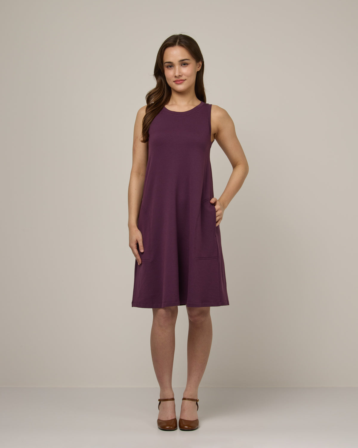 Model wearing Sierra Tank Dress in Marionberry, a dark berry purple color. Sierra Tank Dress is a merino wool sleeveless, crew neck, knee length swing dress with pockets available in sizes XS-3X Regular, XS-3X Long.