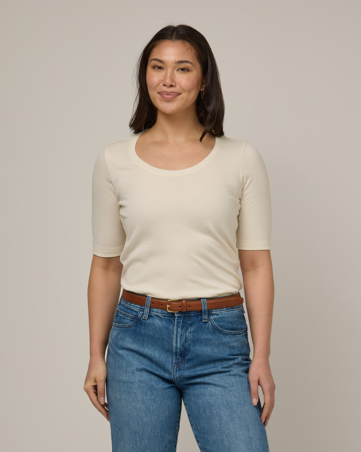 Model wearing Celine Ribbed Elbow Sleeve Tee in Natural White, an off-white cream color. Celine Ribbed Elbow Sleeve Tee is a merino wool short sleeve, scoop neck, slim fit tee available in sizes XS-3X.