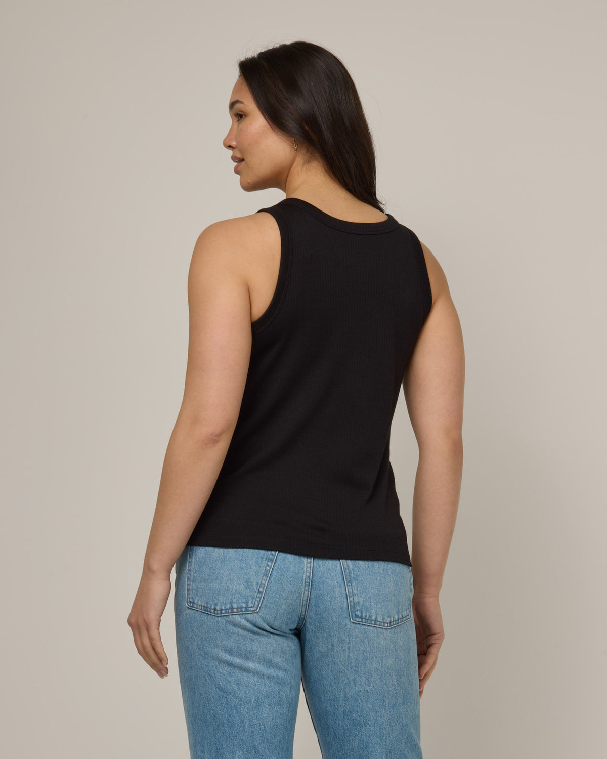 Model wearing Lily Ribbed Tank in Black. Lily Ribbed Tank is a merino wool sleeveless, crew neck, slim fit top available in sizes XS-3X.