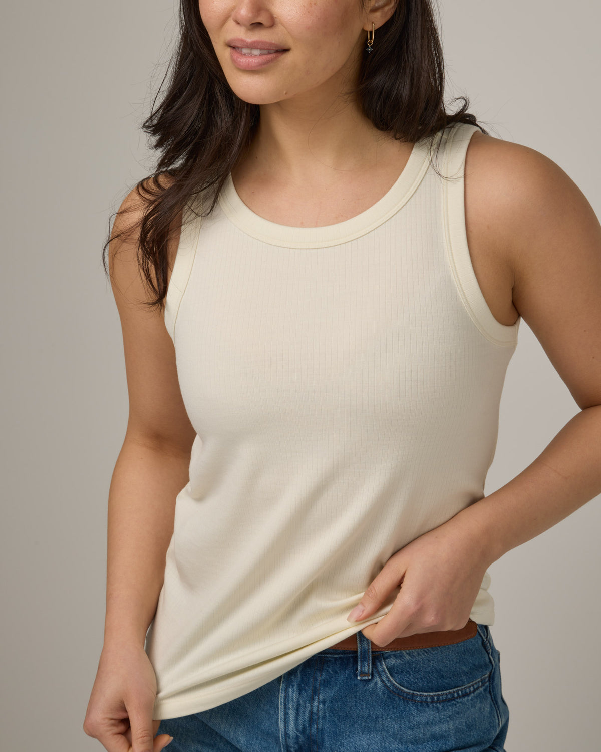 Model wearing Lily Ribbed Tank in Natural White, an off-white cream color. Lily Ribbed Tank is a merino wool sleeveless, crew neck, slim fit top available in sizes XS-3X.