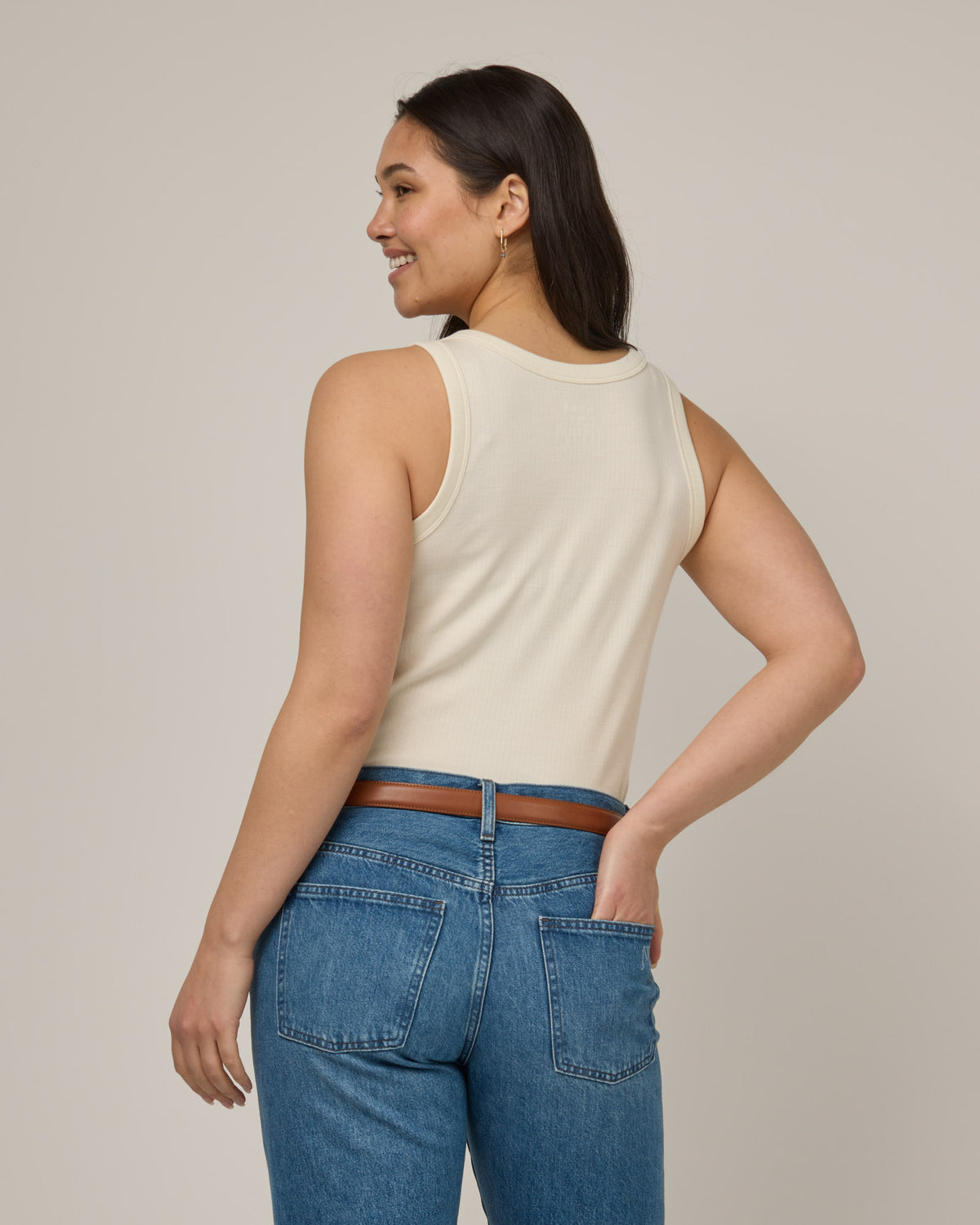 Model wearing Lily Ribbed Tank in Natural White, an off-white cream color. Lily Ribbed Tank is a merino wool sleeveless, crew neck, slim fit top available in sizes XS-3X.