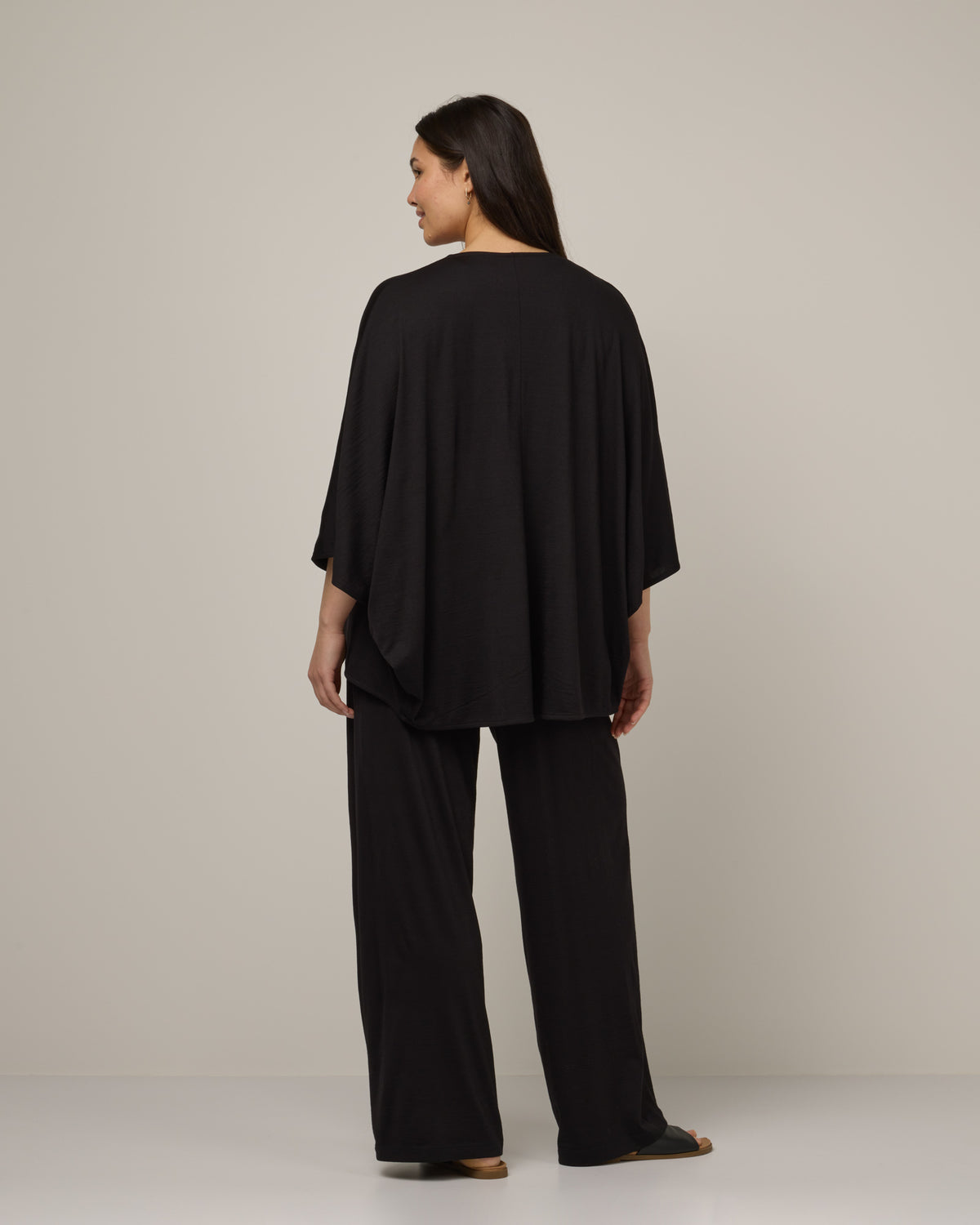Model wearing Lisbon Shawl Cardigan in Black. Lisbon Shawl Cardigan is a merino wool long sleeve, cardigan available in sizes XS-3X.