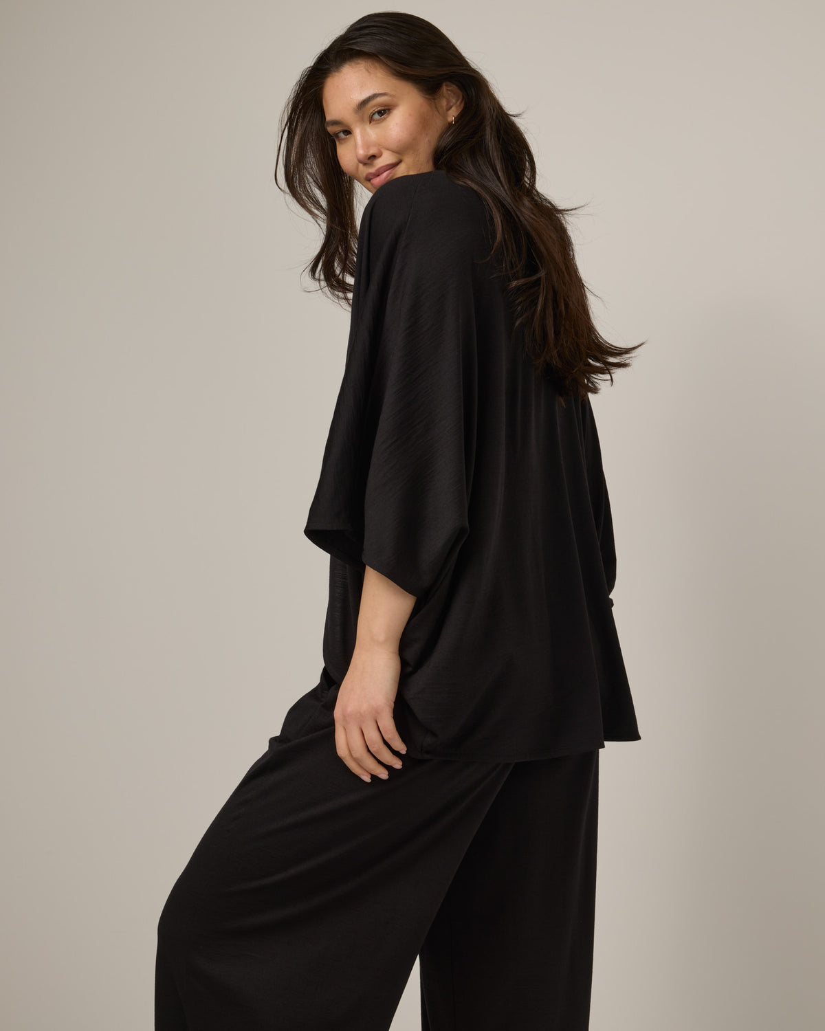 Model wearing Lisbon Shawl Cardigan in Black. Lisbon Shawl Cardigan is a merino wool long sleeve, cardigan available in sizes XS-3X.