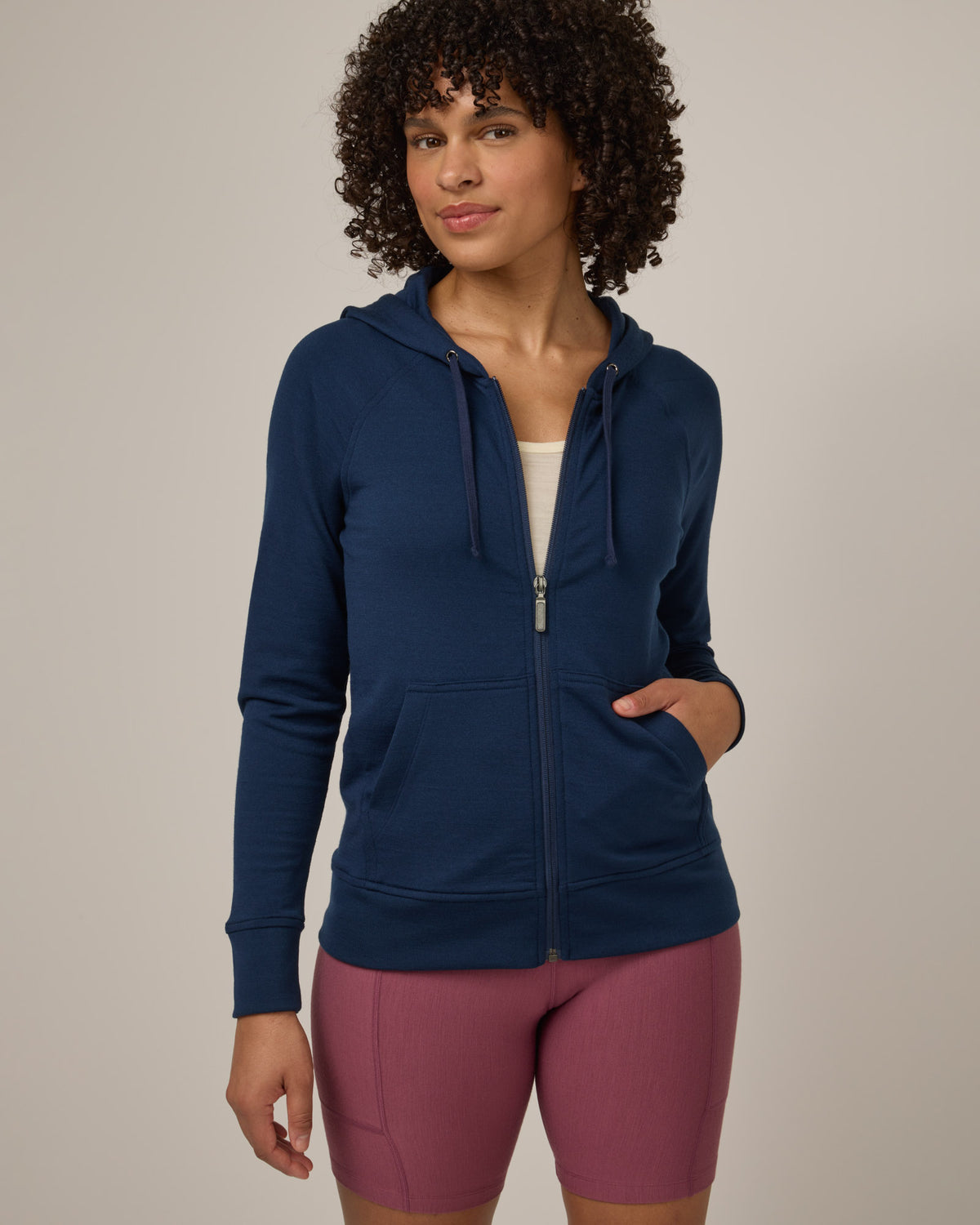 Model wearing Aspen Full-Zip Hoodie in Marine Blue, a deep royal blue color. Aspen Full-Zip Hoodie is a merino wool long sleevezip hoodie with pockets available in sizes XS-3X.