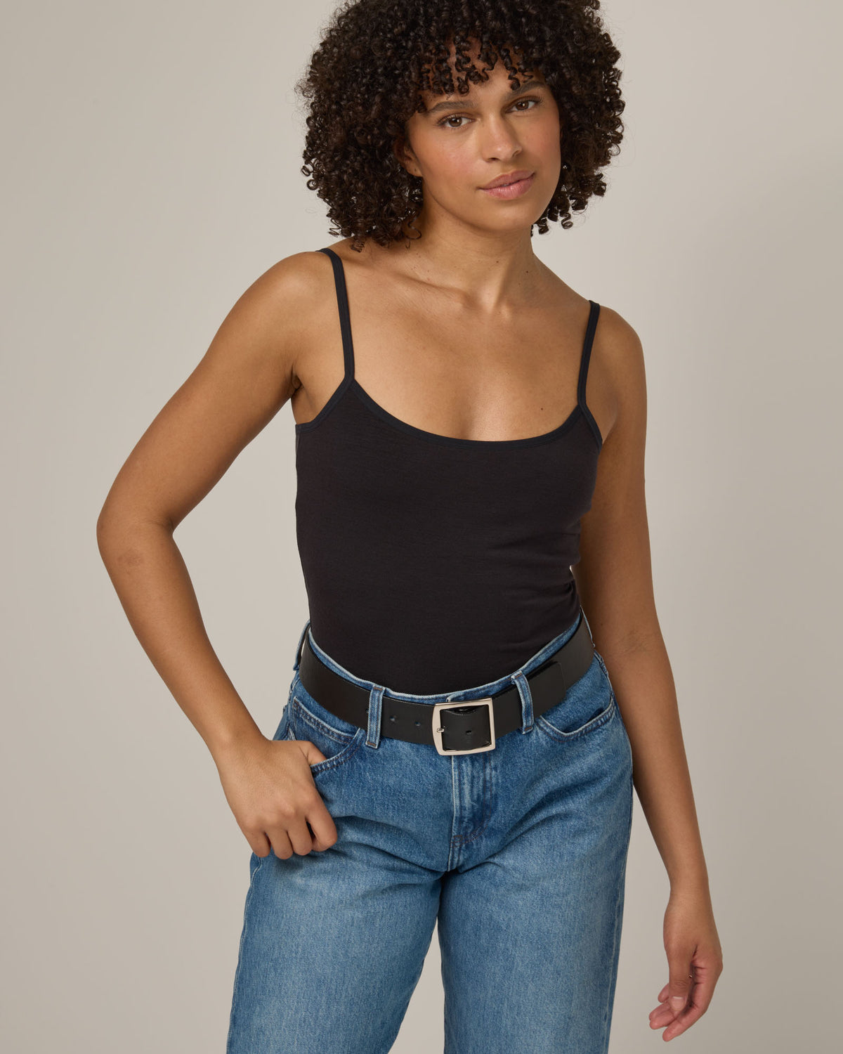 Model wearing Roam Shelf Bra Cami in Black. Roam Shelf Bra Cami is a merino wool sleeveless, scoop neck, slim fit top available in sizes XS-XXL.