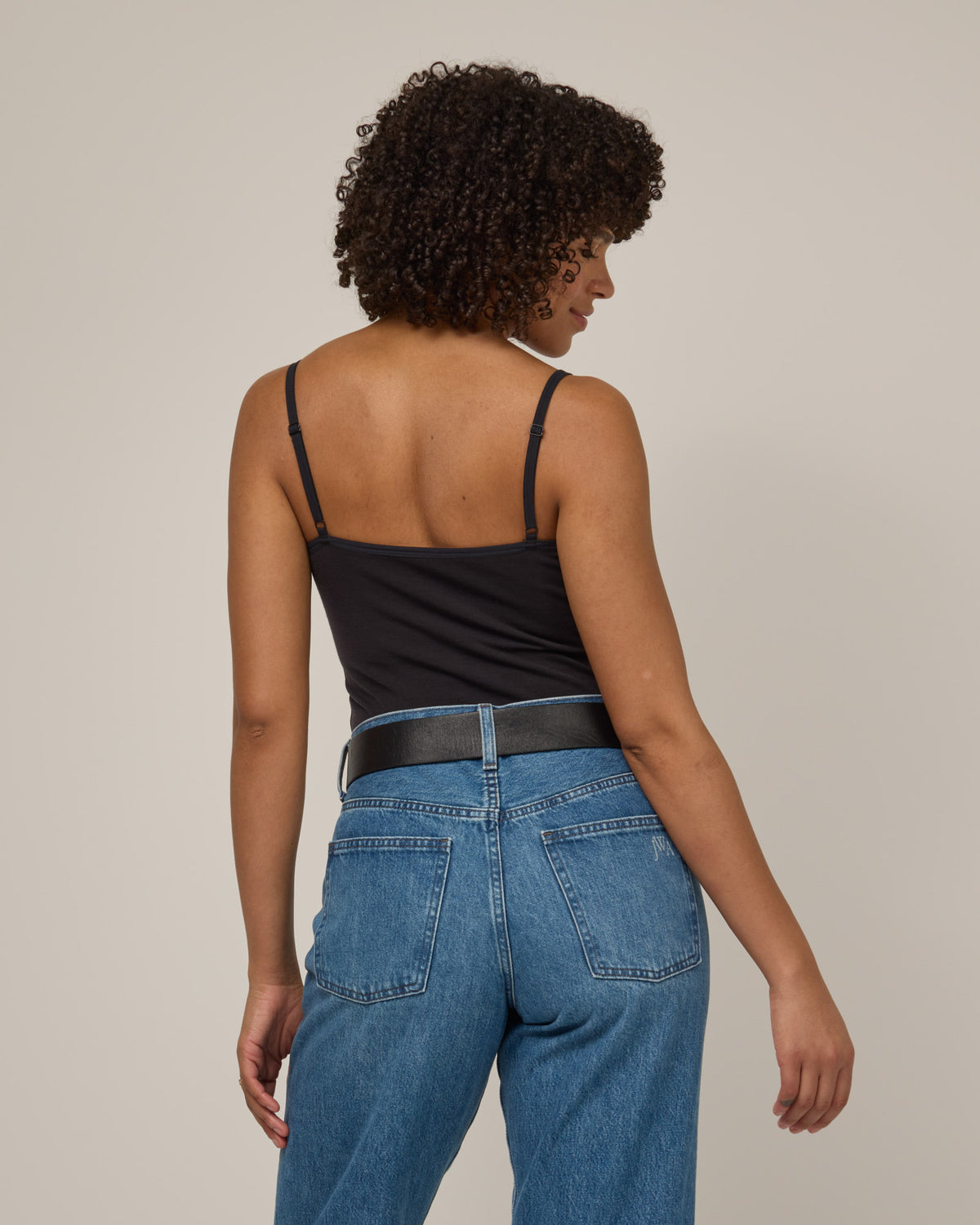 Model wearing Roam Shelf Bra Cami in Black. Roam Shelf Bra Cami is a merino wool sleeveless, scoop neck, slim fit top available in sizes XS-XXL.