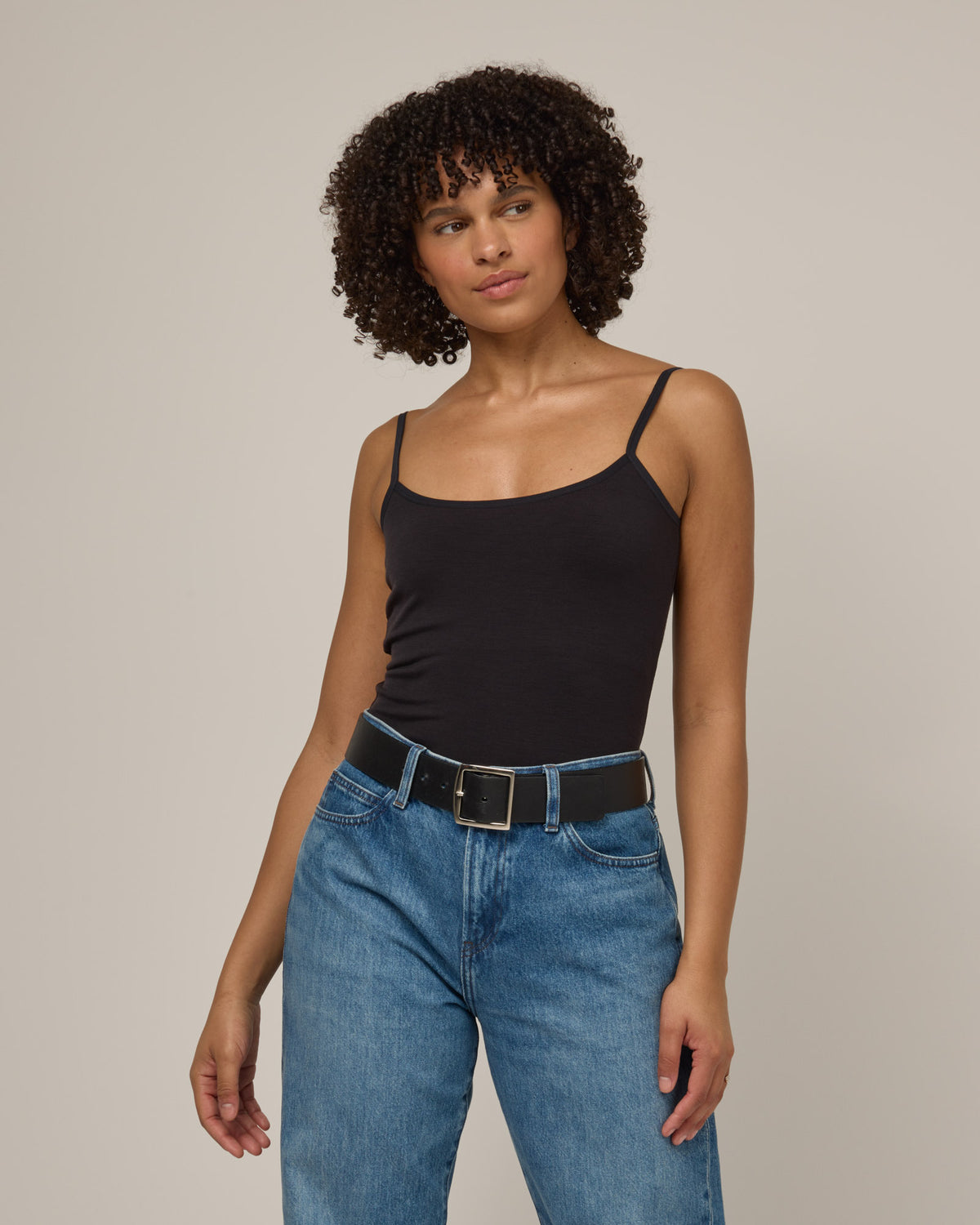 Model wearing Roam Shelf Bra Cami in Black. Roam Shelf Bra Cami is a merino wool sleeveless, scoop neck, slim fit top available in sizes XS-XXL.