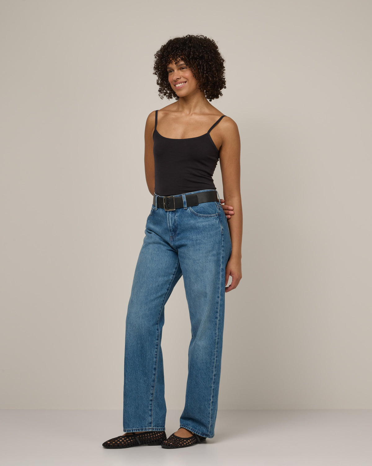 Model wearing Roam Shelf Bra Cami in Black. Roam Shelf Bra Cami is a merino wool sleeveless, scoop neck, slim fit top available in sizes XS-XXL.