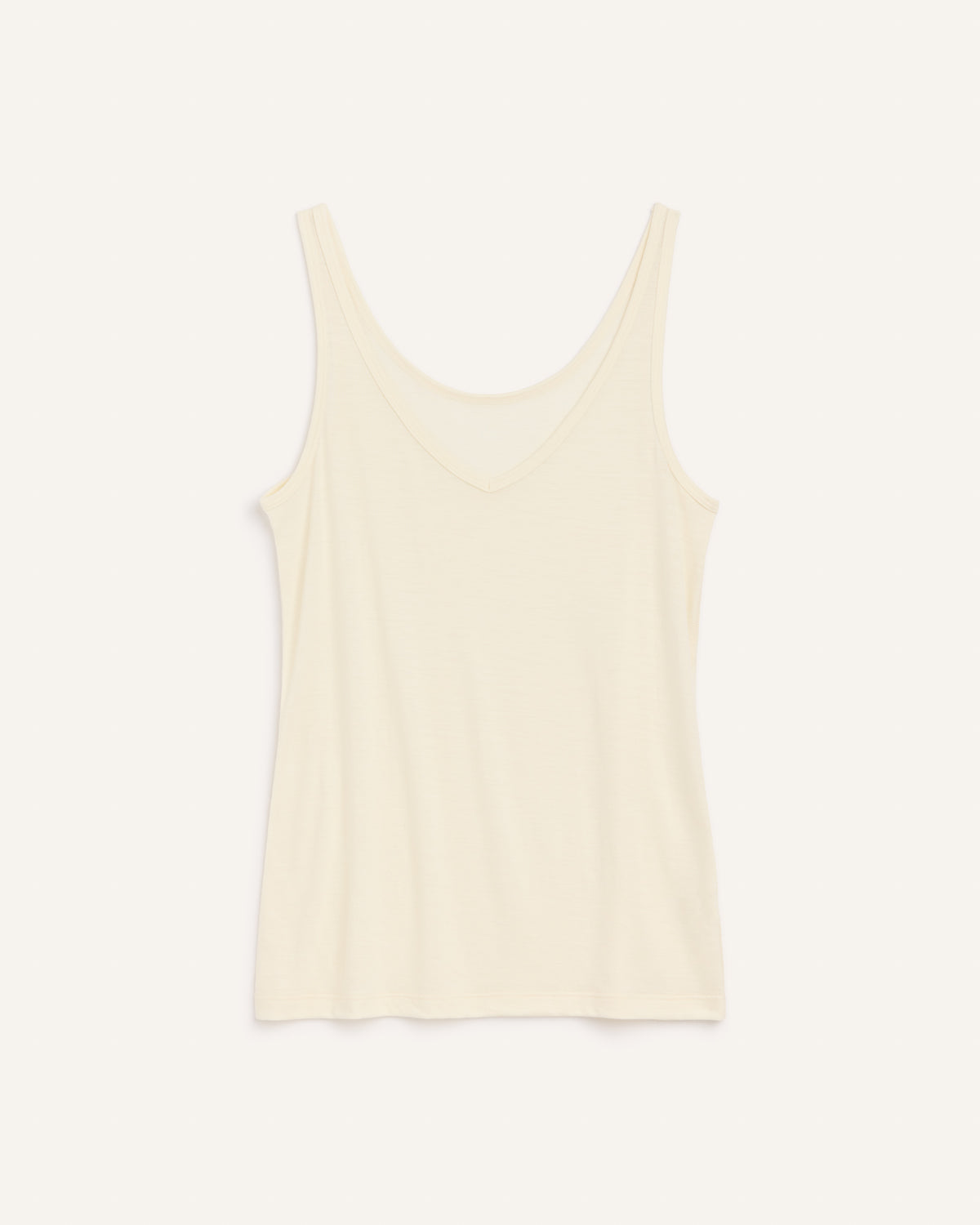 Laydown of Essential Layering Tank in Natural White, an off-white cream color. Essential Layering Tank is a merino wool sleeveless, reversible, slim fit top available in sizes XS-3X.