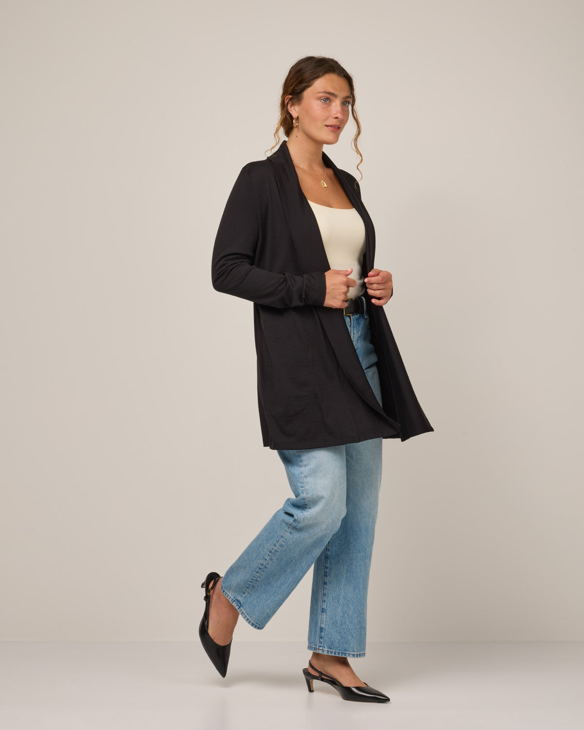 Model wearing Landmark Cardigan in Black. Landmark Cardigan is a merino wool long sleevecardigan with pockets available in sizes XS-3X.