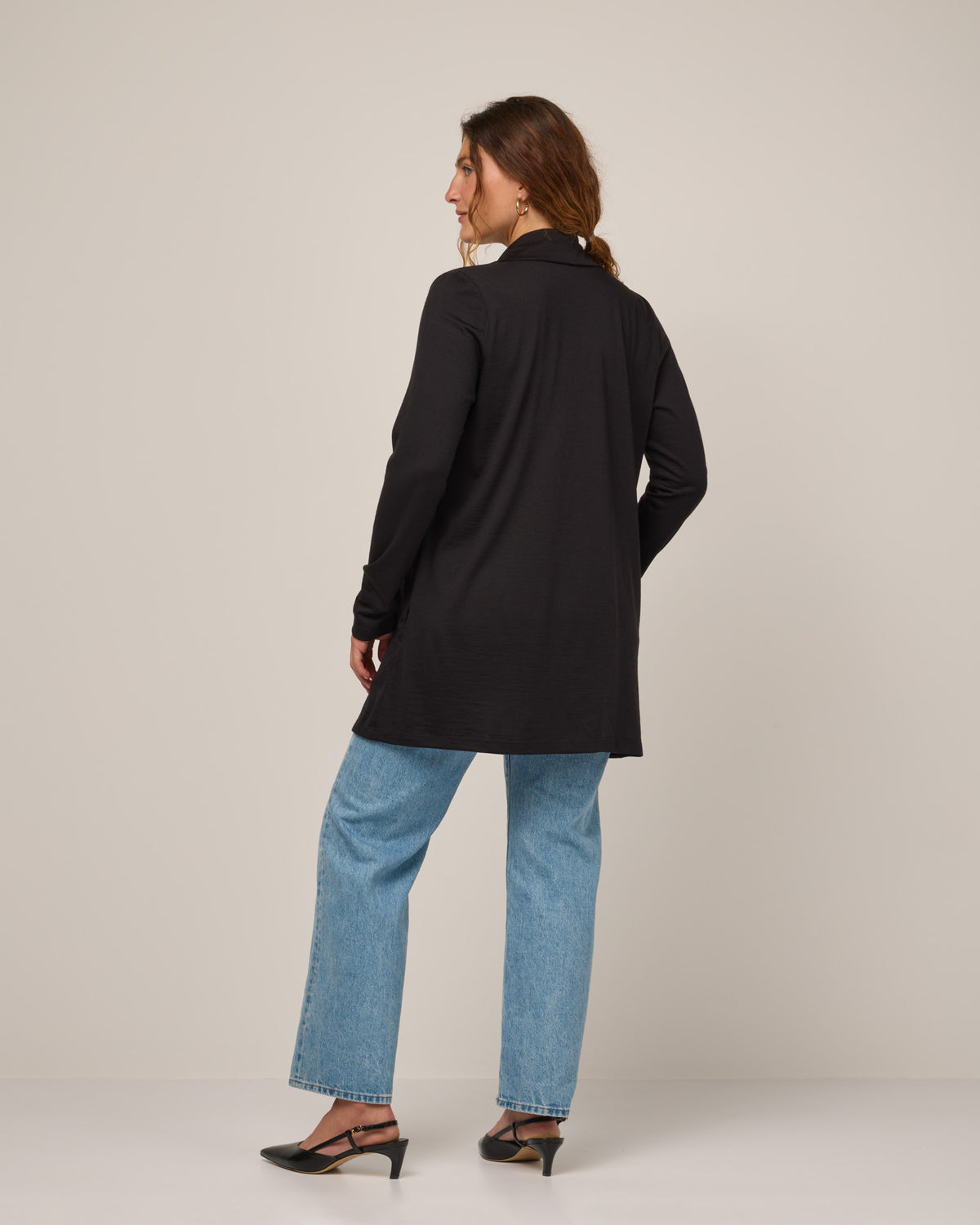 Model wearing Landmark Cardigan in Black. Landmark Cardigan is a merino wool long sleevecardigan with pockets available in sizes XS-3X.
