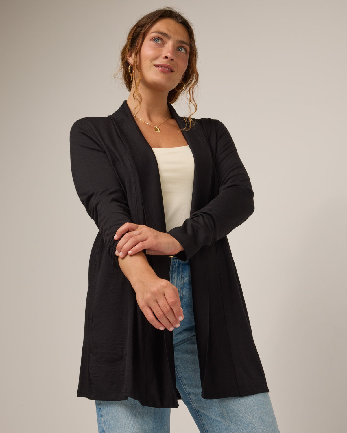 Model wearing Landmark Cardigan in Black. Landmark Cardigan is a merino wool long sleevecardigan with pockets available in sizes XS-3X.