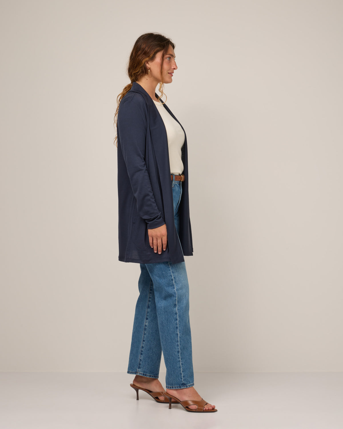 Model wearing Landmark Cardigan in Washed Navy. Landmark Cardigan is a merino wool long sleevecardigan with pockets available in sizes XS-3X.