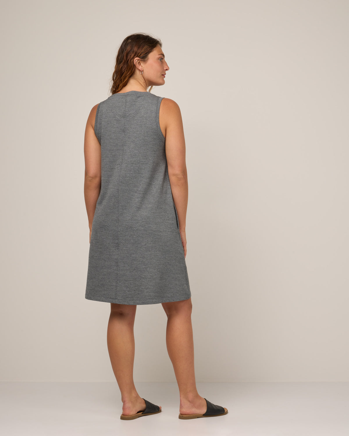 Model wearing Sierra Tank Dress in Charcoal Heather. Sierra Tank Dress is a merino wool sleeveless, crew neck, knee length swing dress with pockets available in sizes XS-3X Regular, XS-3X Long.