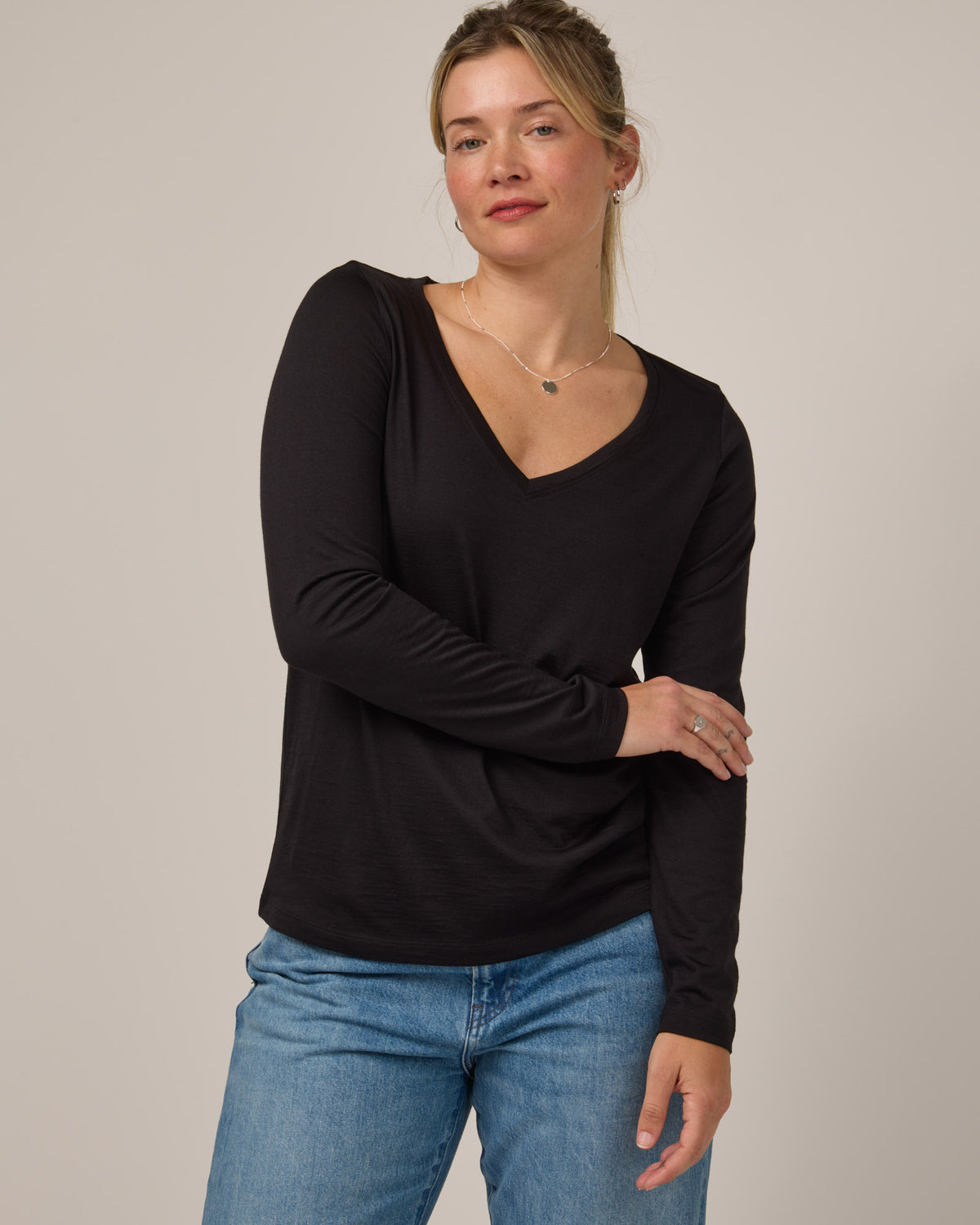 Model wearing Brenton V-Neck Tee in Black. Brenton V-Neck Tee is a merino wool long sleeve, v-neck, regular fit tee available in sizes XS-3X.